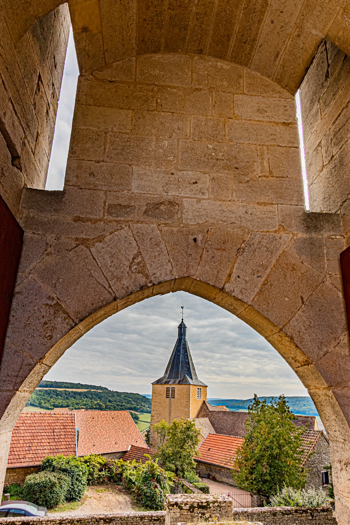 L'église de Saint-Philippe et Saint-Jacques de Châteauneuf-en-Auxois vue à travers un trou dans l'enceinte du château.