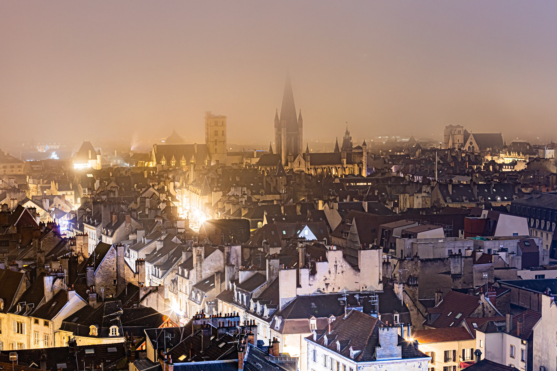 Vue aérienne de Dijon de nuit dans le brouillard, sur la tour Philippe Le Bon, le clocher  de l'église Notre-Dame et la coupole du musée d'art sacré.