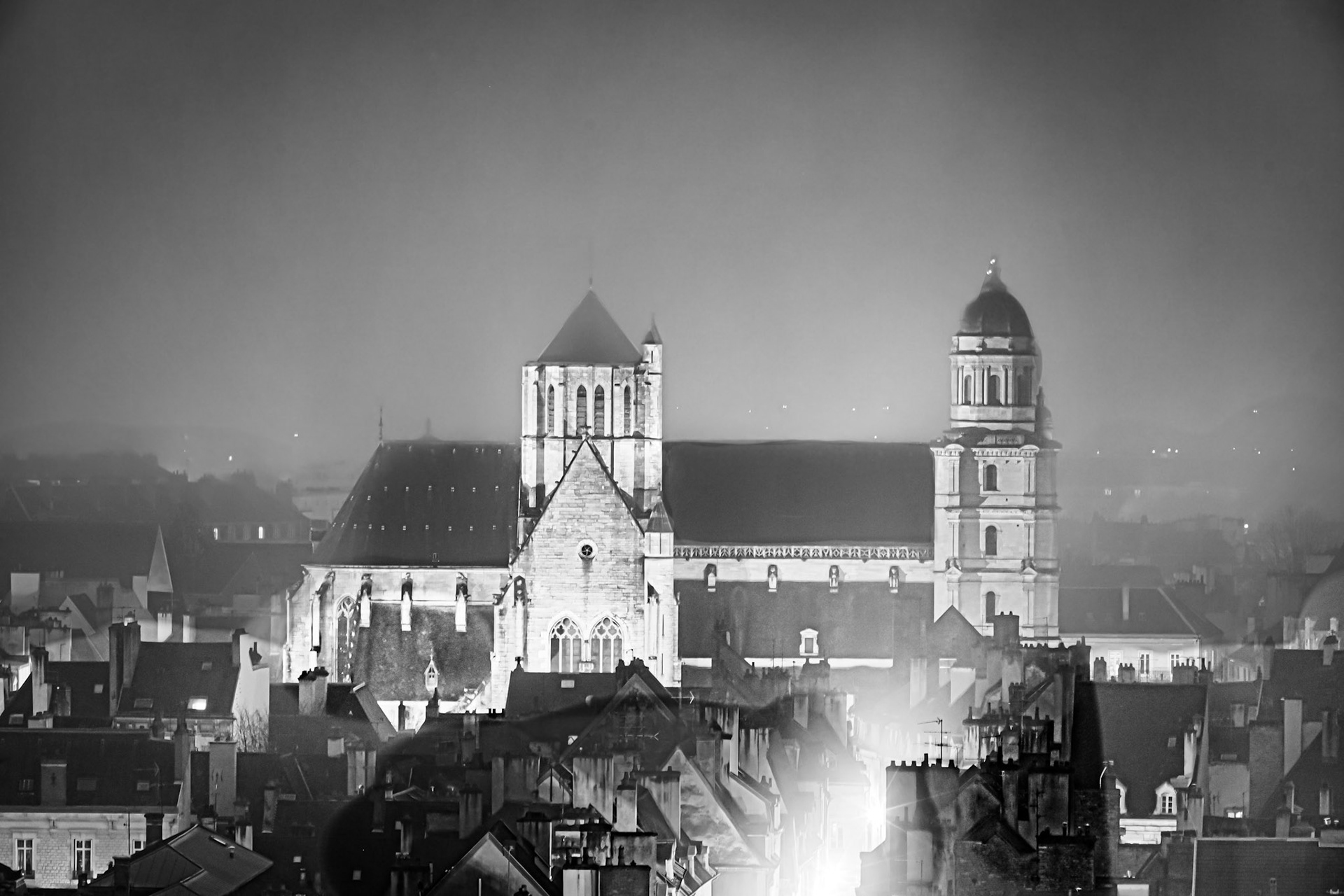 Vue aérienne de Dijon en noir et blanc, dans le brouillard, sur la tour Philippe Le Bon, le clocher  de l'église Notre-Dame et la coupole du musée d'art sacré.