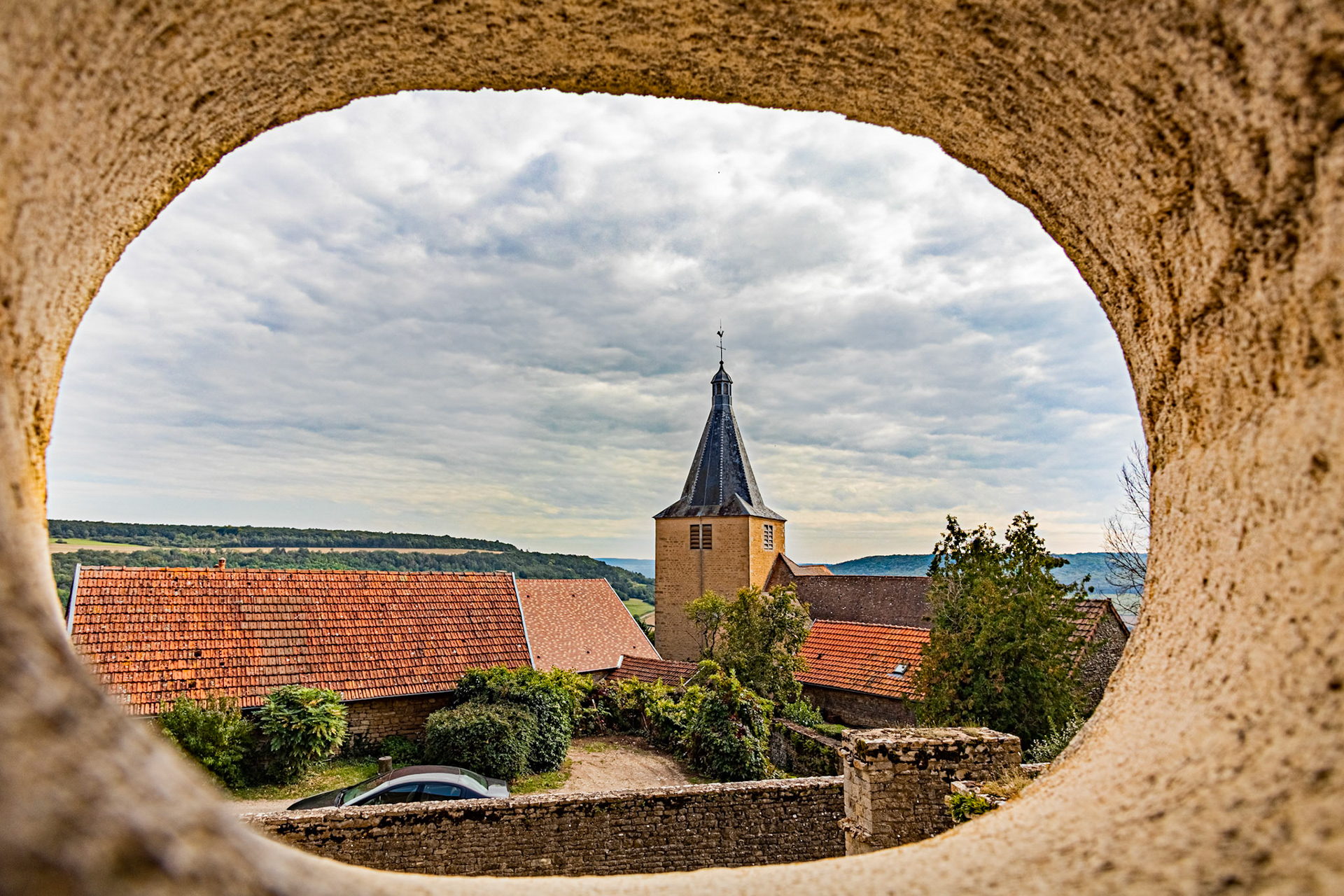 L'église de Saint-Philippe et Saint-Jacques de Châteauneuf-en-Auxois vue à travers un trou dans l'enceinte du château.