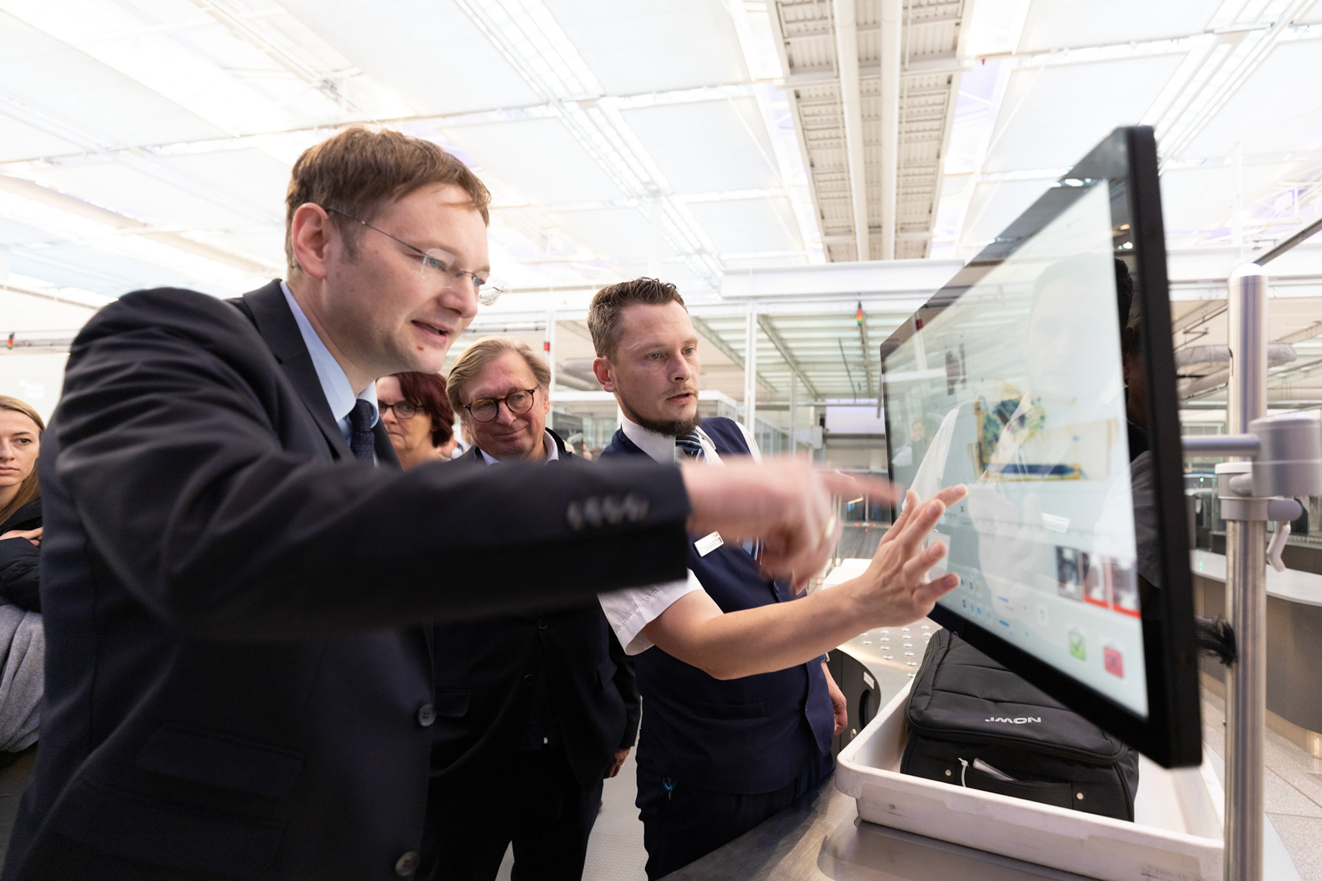 Hans Reichhart, Michael Kerkloh and security staff member try out a new fast lane system at MUC
