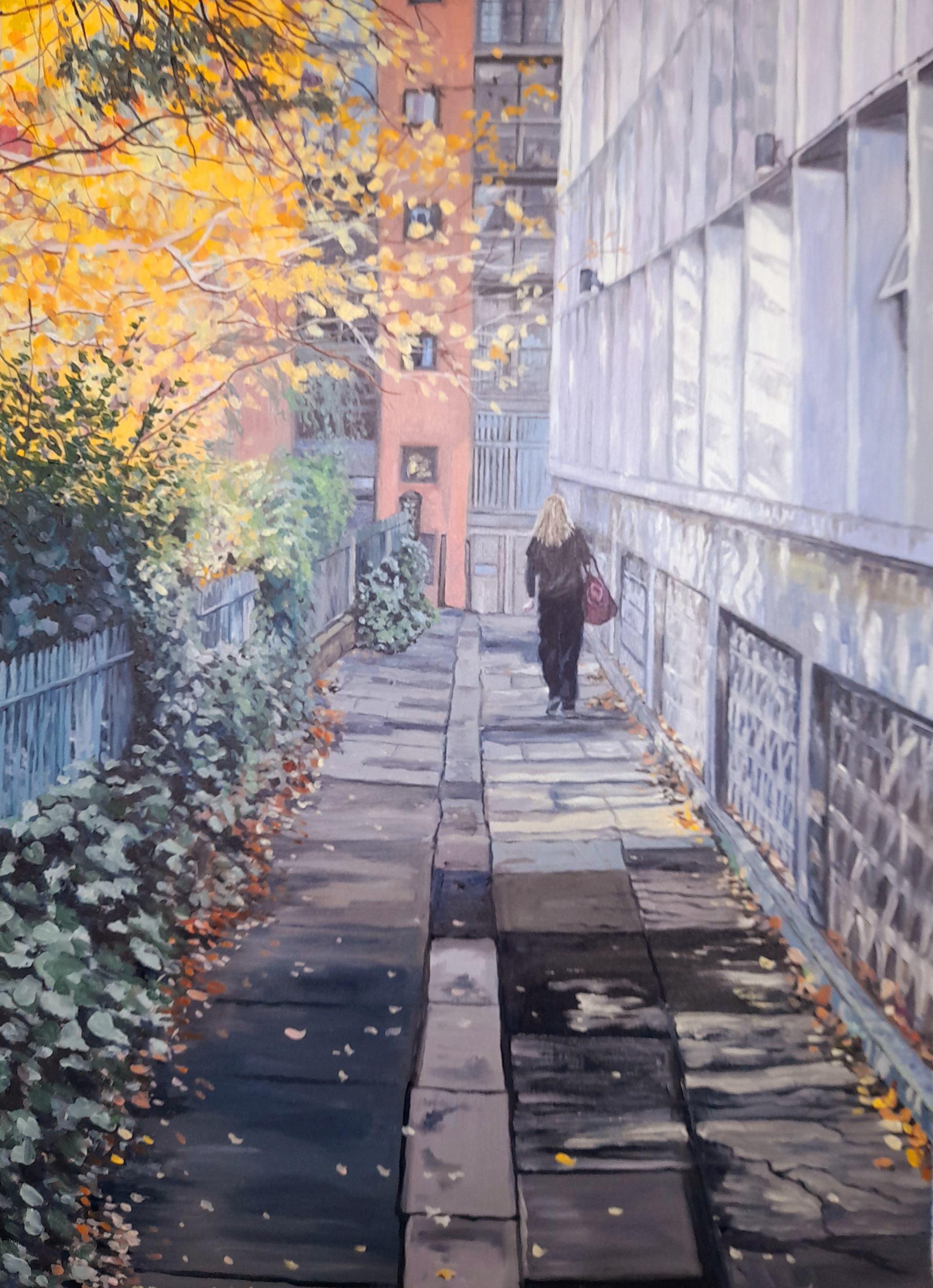 “Passageway next to St John’s Gardens, Manchester” Kathryn Nuttall, Oil on canvas, 2026 “This painting depicts a walkway beside St John's Gardens in central Manchester, a transitional space where nature and the built environment exist in close proximity. I was drawn to the scene by the contrast between the trees and shrubs bordering the gardens and the stark concrete façade of the adjacent office building. The composition explores the tension between the organic and the constructed, a recurring theme throughout my work. Painted from observations made in early November, the work captures a fleeting seasonal moment. Amber and yellow leaves illuminate the upper part of the scene, while others drift to the pavement below, creating a sense of movement and impermanence. As I was sketching, a young woman walking through the passage while looking at her phone provided a human presence, introducing a contemporary narrative and a sense of scale within the urban landscape. This painting forms part of a wider body of work investigating climate change through locations within a fifteen-mile radius of Manchester. Influenced by the Romantic tradition, I am interested in how moments of natural beauty continue to exist within environments shaped by human activity. Romantic artists sought emotional and spiritual engagement with nature, often responding to its power and transience. Today, as concerns about climate change, biodiversity loss and environmental degradation become increasingly urgent, these themes take on renewed relevance. St John's Gardens itself embodies the layered relationship between people, history and nature. Created on the site of the former churchyard of St John's Church, the gardens contain the remains of more than 22,000 people and have evolved into an important green space within the city centre. The presence of mature trees, including species valued for their resilience in urban conditions, highlights nature's ability to endure and adapt within heavily developed environments. By juxtaposing the softness of autumn light and foliage with the solidity of concrete architecture, the painting reflects both the fragility and resilience of the natural world. It invites viewers to pause and consider the importance of these everyday urban green spaces and the role they play in sustaining both ecological diversity and human wellbeing.” @tempest_arts_kn