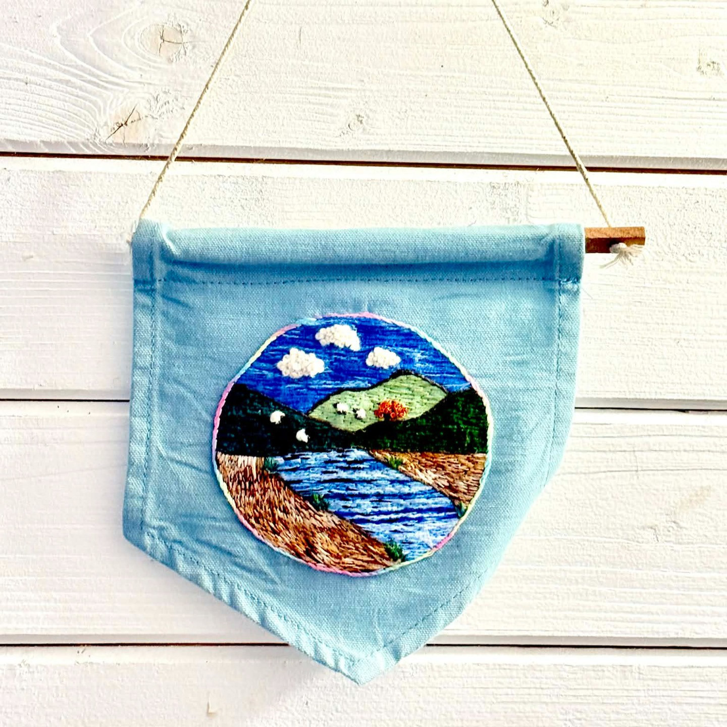 “A view from Rainbow's End” Laura (fLaura & fauna healing stitches), hand embroidery, 2025 “In the summer of 2025, I was unwittingly getting closer and closer to burnout. Years of being stuck in fight or flight was slowly chipping away at my functioning, my mood and my work-life balance.  I didn't recognise it, but my brain and nervous system were in overdrive. I'd desperately search for things to help with the overwhelm and anxiety, often trying hobby after hobby, but never being able to stick to anything or find anything that really helped.  I had bought a basic embroidery kit that summer, as another attempt at trying to calm my poor brain, and for some reason when I started that simple kit, my brain felt like it was being told it was safe.  Since then, I have developed my skills and started going to a weekly stitching group, and it's quite frankly saved my life.  In October, just a few months after discovering embroidery, a friend had his life turned upside down when he had a stroke at age 47. My nervous system was yet again on high alert, remembering the feelings of previous trauma, except this time, I could turn to embroidery. He owns a boat called Rainbow's End, which is a floating haven of calm, so whilst he was in hospital trying to recover his life and function back, I started this piece. By the time it was ready, it was perfect for his Christmas present, and represents my solace during those 3 months, his progress, and is the calm pot of gold at the end of the rainbow.  I'd love to help show you that even when your brain is struggling, busy, stuck in fight or flight, or always on the go from past trauma, that healing can start from just a needle and thread.” @flaurafaunahealingstitches