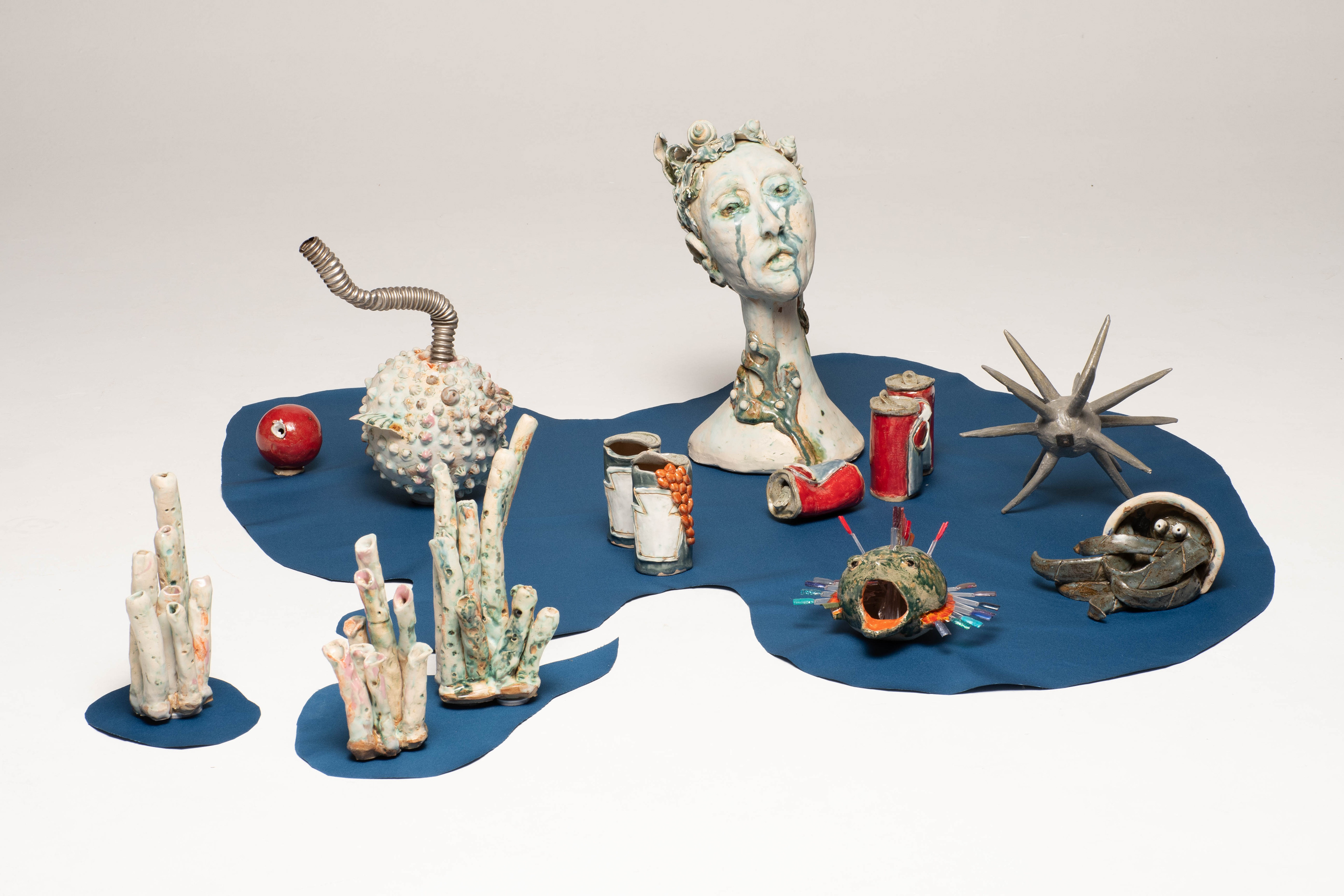 “Shed Salty Tears” Helen Birnbaum, Ceramic and reclaimed media, 2023 “In 2023, 480,343 pieces of litter were found on UK beaches, by 2024 this had become 764,451.. The fish, marine animals and birds that become caught in plastic rubbish suffocate, stave and drown: hundreds of marine species have been harmed by the debris we leave in our oceans. As our planet faces greater and greater environmental problems I strive to create work that combines important ecological messages alongside sustainable practice. Shed Salty Tears draws attention to the bleaching of the sea bed and pollution and consists of many ceramic pieces which are integrated with found objects.  Calling us to take notice of this environmental crisis is the statue of a woman at the centre of the ceramic installation Shed Salty Tears; the voice of the planet, calling us to notice the state of our environment degraded by industrialisation. Crushed cans, rusty metal forms and discarded plastic cluster around the central sculptures. Reclaimed materials challenge viewers to consider what they consume and how it is discarded.  Shed Salty Tears is a triptych with each of the three separate sections having their own particular emphasis. Each section has approximately fifty white, grey and blue shells, corals and other sea life surrounding three large central sculpted figures; a telephone; an African harp and a crying figure shedding salty tears. In striking contrast brightly coloured ceramic made red, orange and green drinks cans, milk bottles and baked bean cans suggest the detritus causing damage to our seas and beaches.  Shed Salty Tears also includes a selection of bizarre sea creatures envisaged as part organic and part metal debris suggesting that because of the rubbish we throw into the sea this is what the creatures might even become - part organic matter and part the rubbish we humans have left behind.” helenbirnbaumceramics.com  @helenbirnbaumceramics