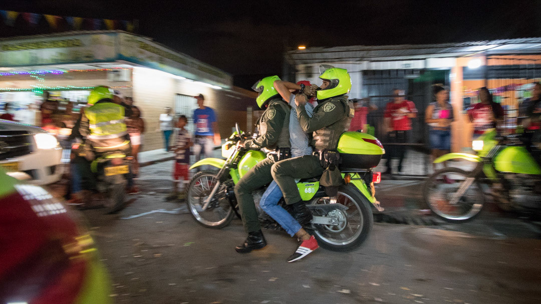 Police officers arresting a man during a night raid in Cali, Colombia.