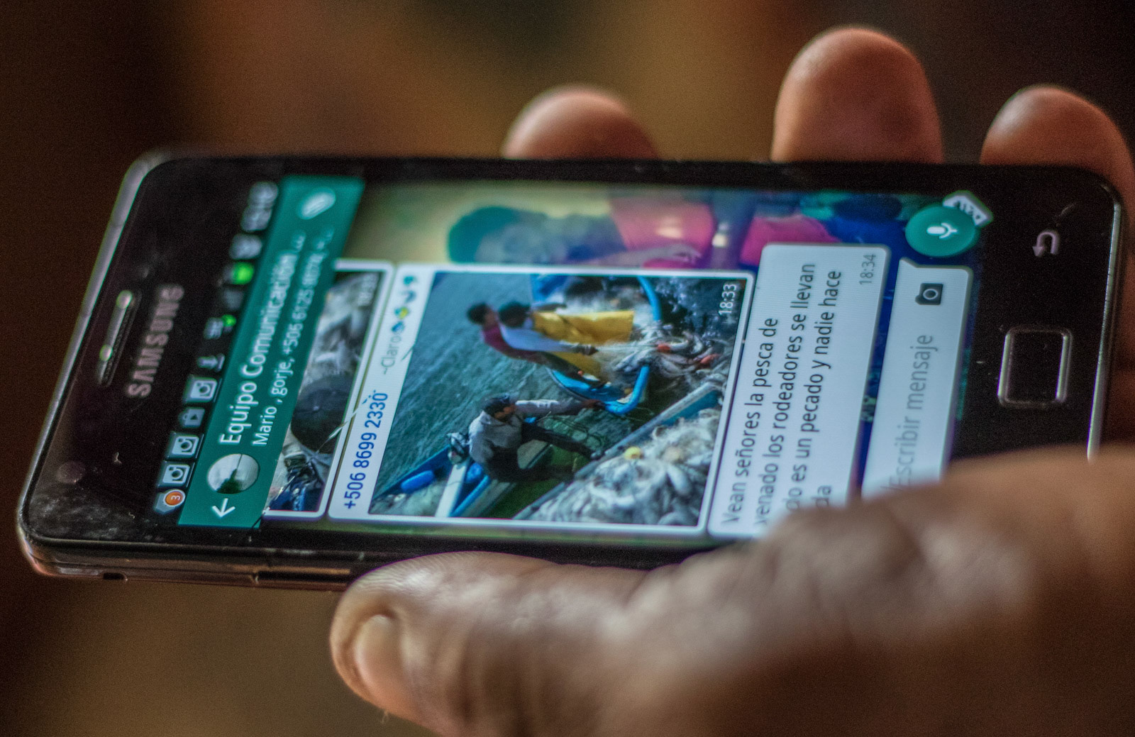 Umaña checks a WhatsApp message showing people fishing illegally in their area.