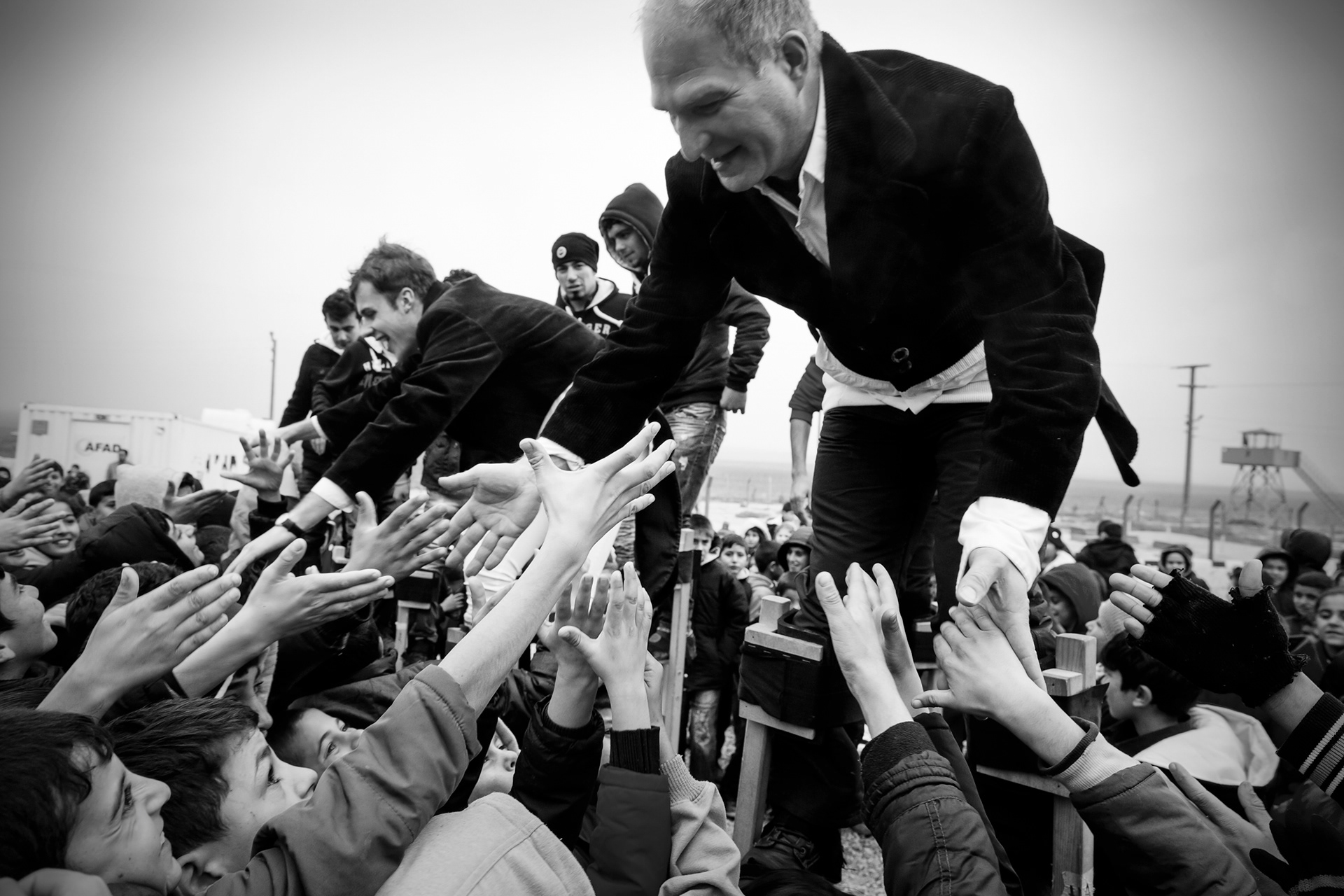 Refugee children are trying to shake hands with the intructors after a stilt performance