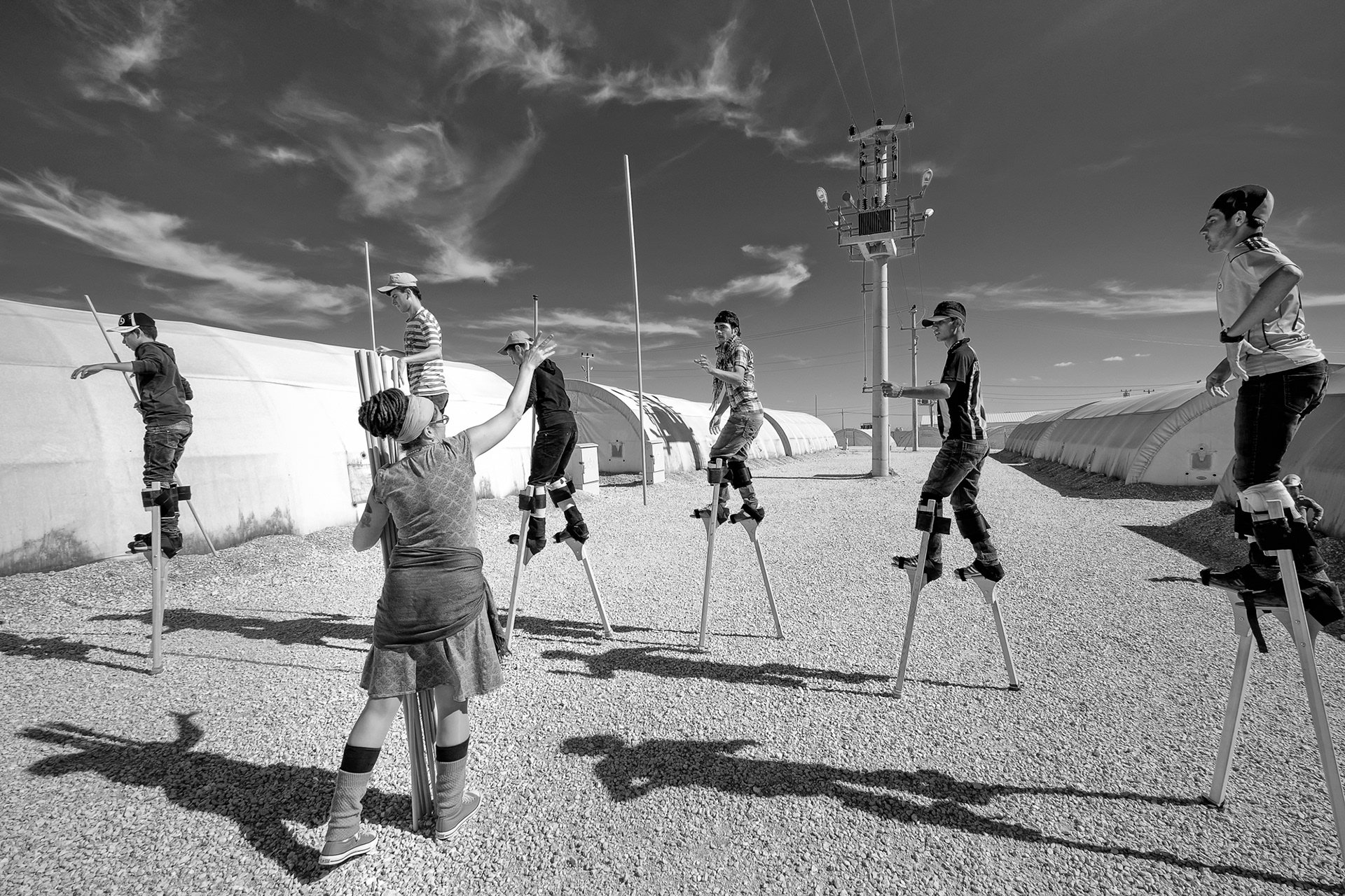 Being able to do multiple tasks while walkign with stilts needs lots of practice. Nusaybin Refugee Camp, Mardin