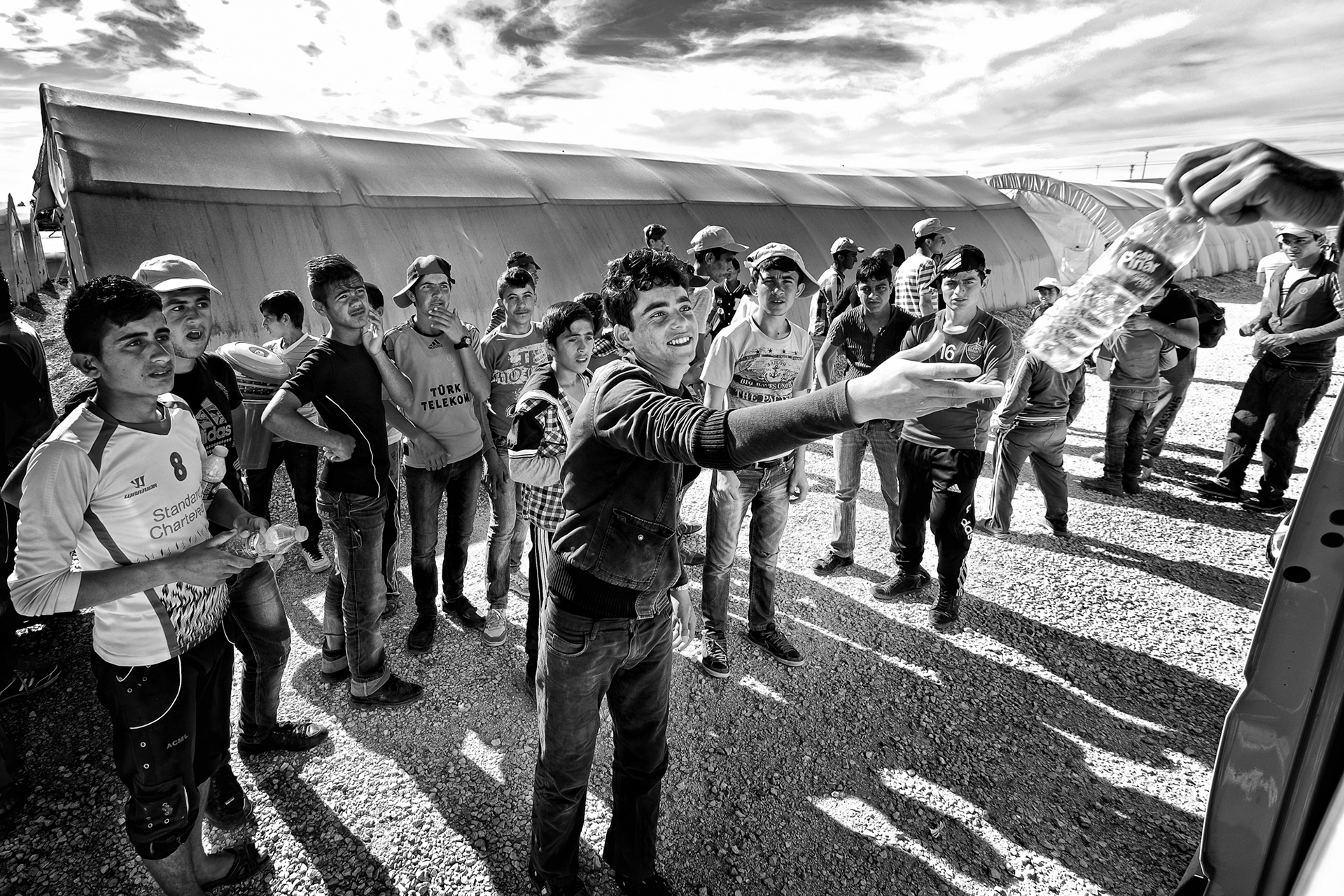 A volunteer is sharing his water with a refugee boy before leaving the camp area. Nusaybin Refugee Camp, Mardin