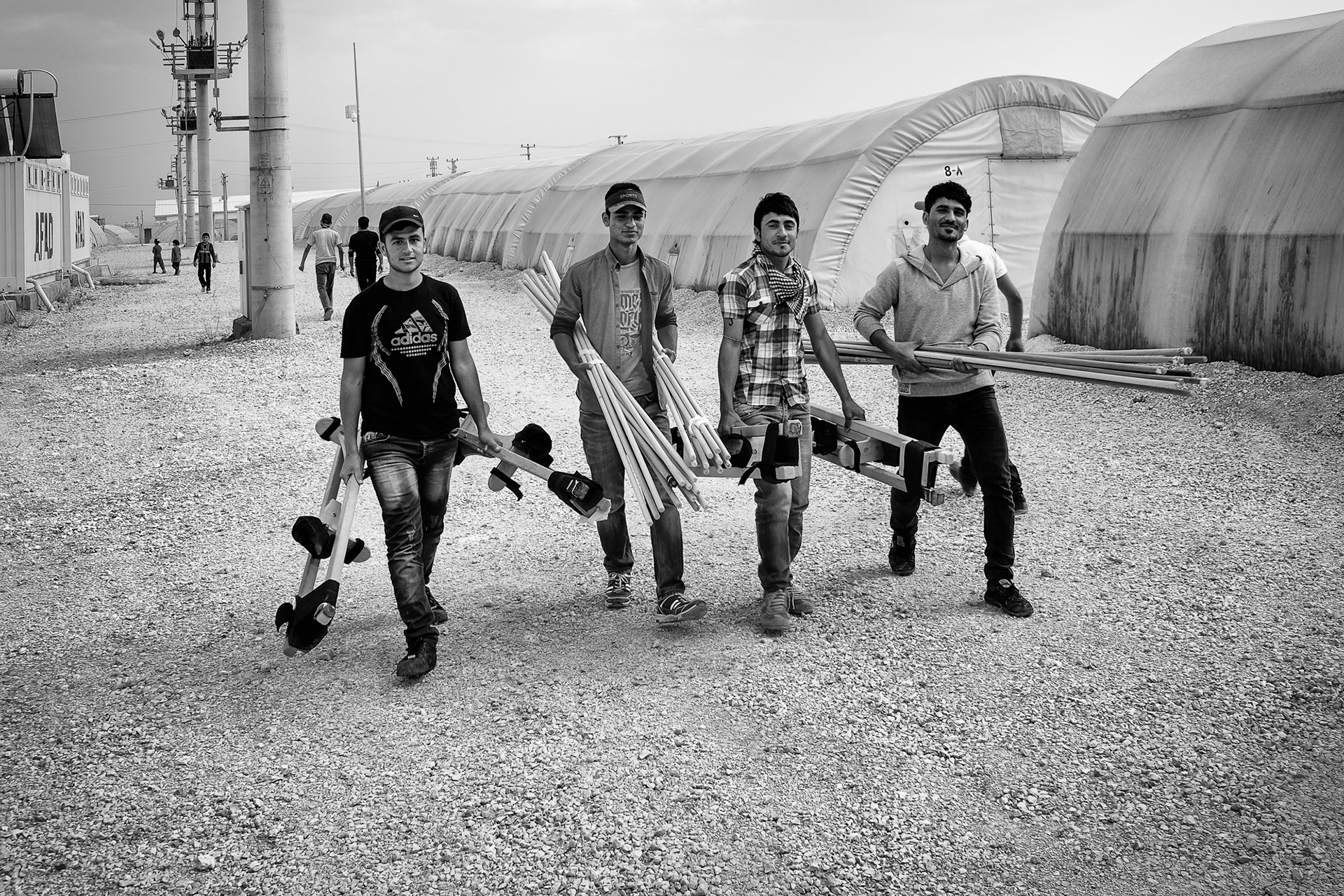 Young adults walking to the training area inside the refugee camp where they will practice walking and performing on the stilts.