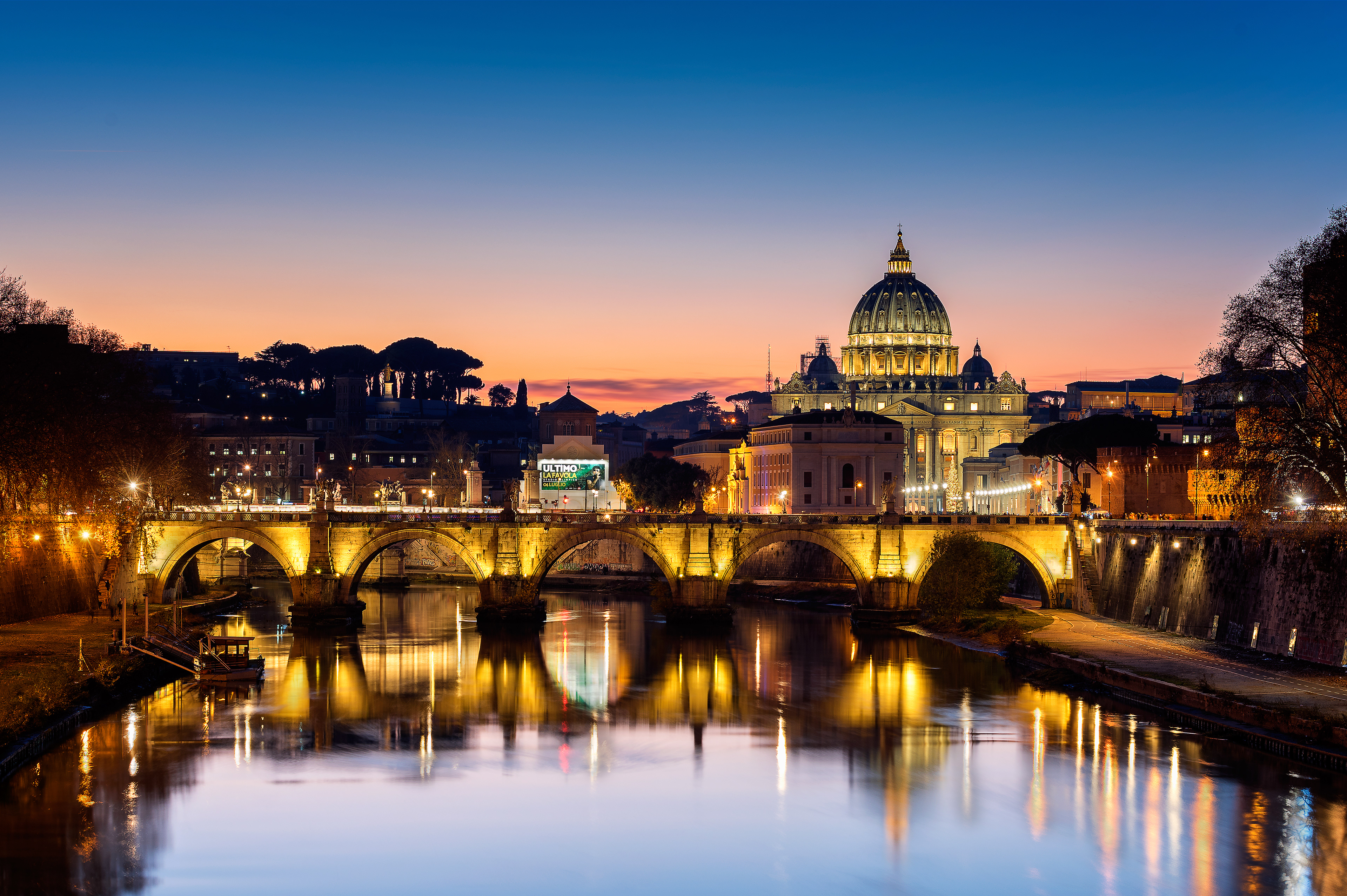 The dome of St. Peter’s Basilica and the arches of Ponte Sant'Angelo beautifully illuminated and reflected in the Tiber River at twilight