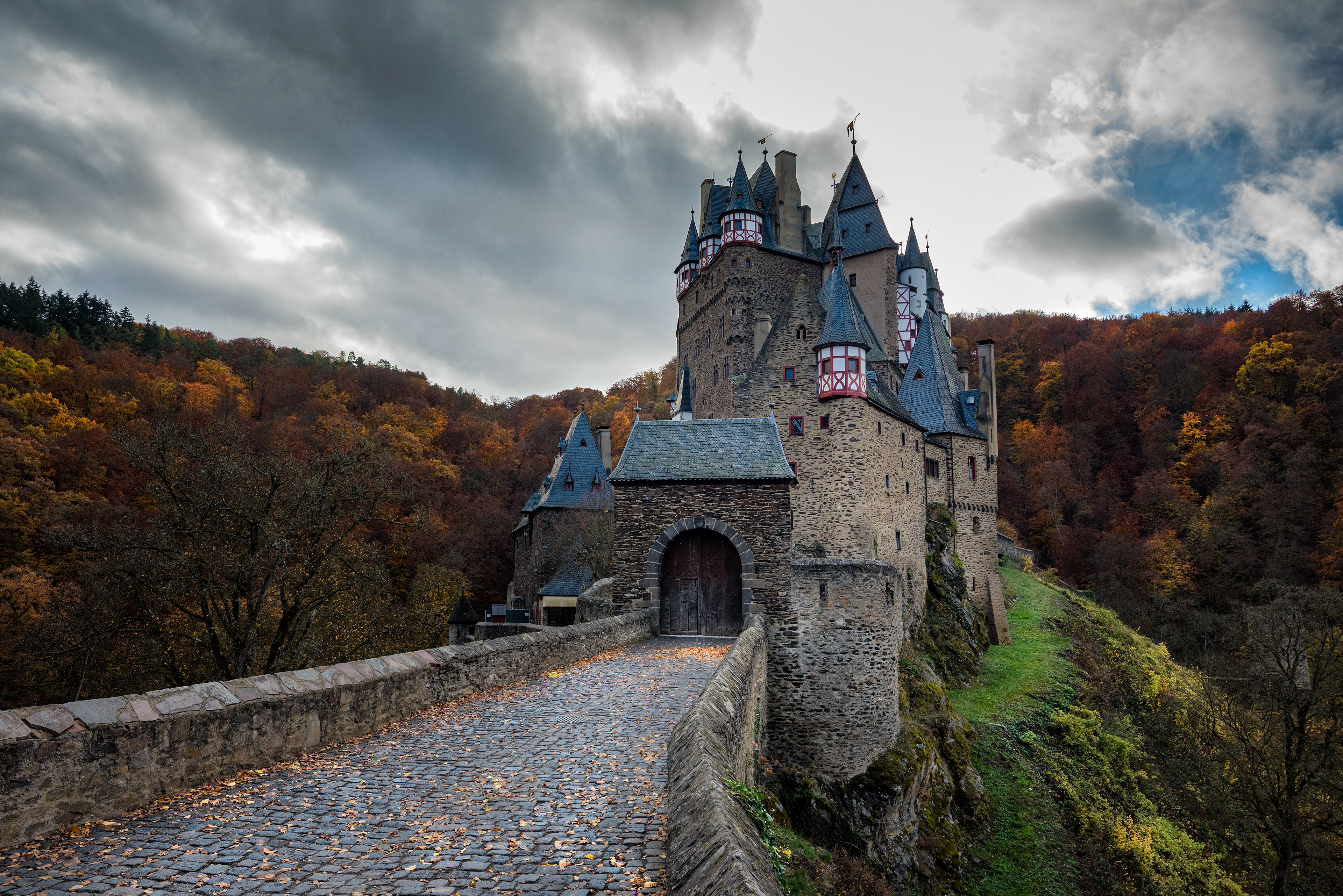 The medieval Eltz Castle (Burg Eltz) tucked away in a vibrant autumn forest, accessible only by a narrow stone bridge