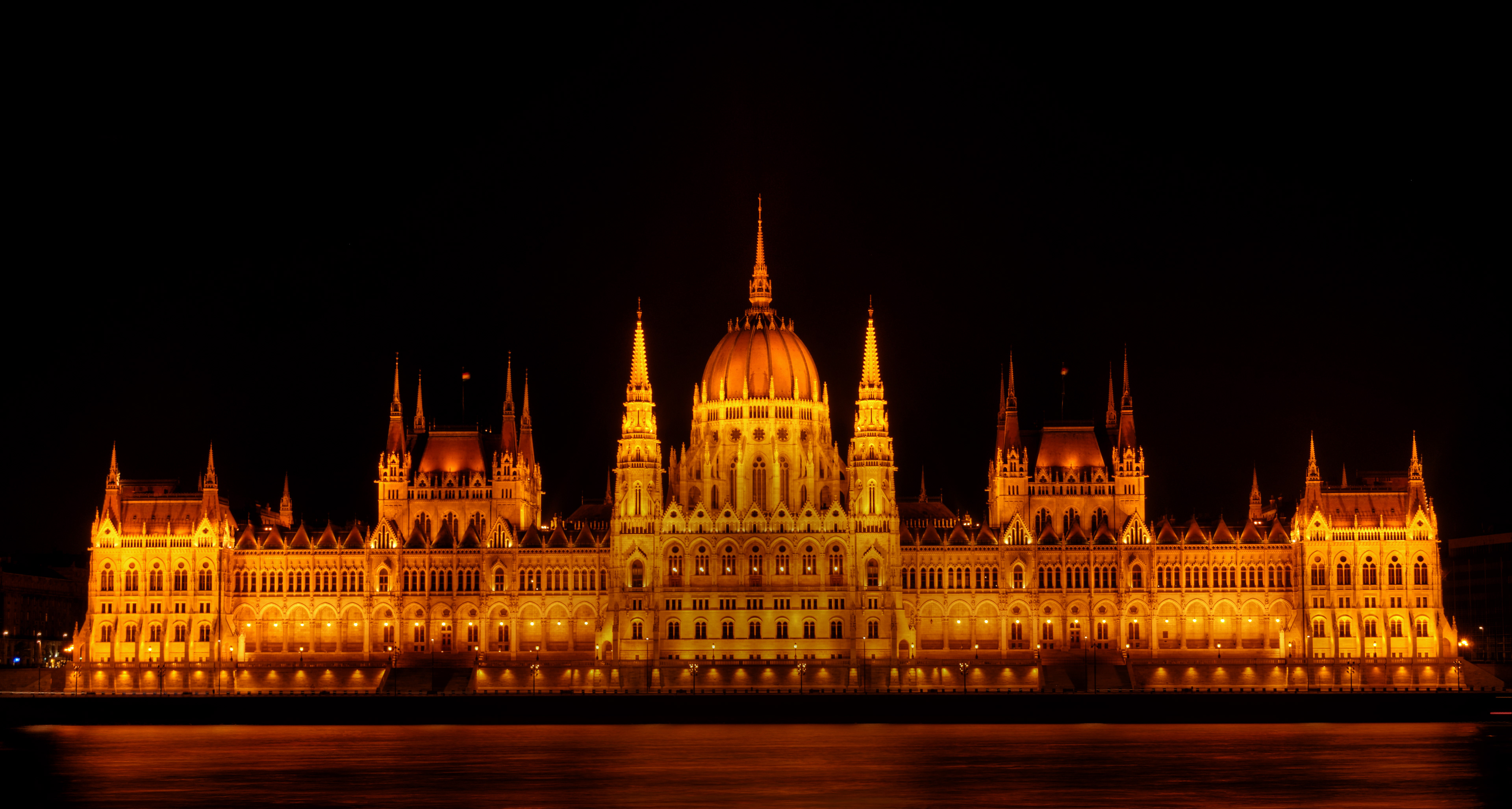 The Hungarian Parliament Building glowing in gold against the night sky, its reflection shimmering perfectly across the Danube River.