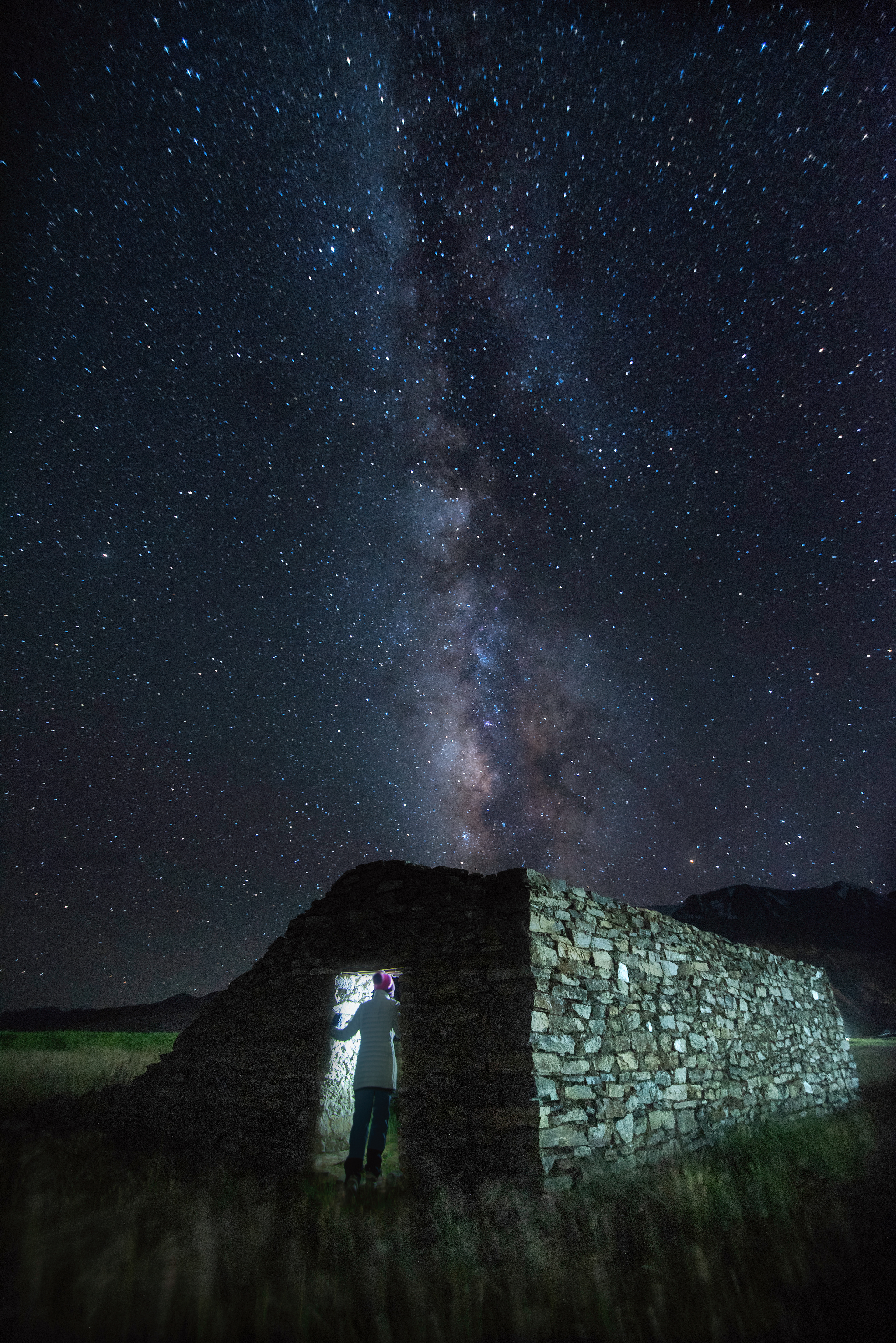 The Milky Way galaxy rising vertically above a lonely stone hut in the remote, light-pollution-free skies of Ladakh