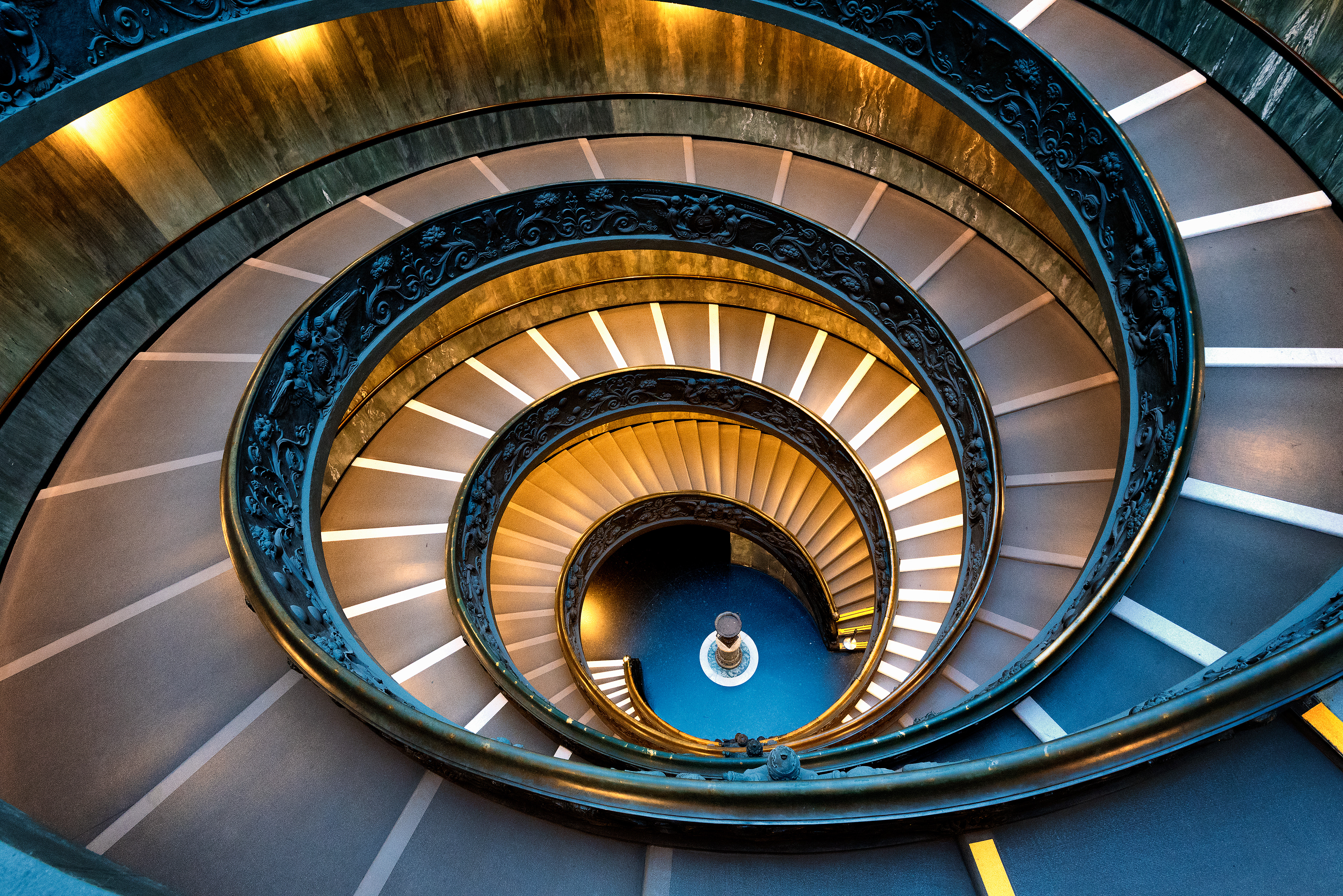 The mesmerizing double-helix spiral of the Bramante Staircase in the Vatican Museums, drawing the eye into its illuminated core.