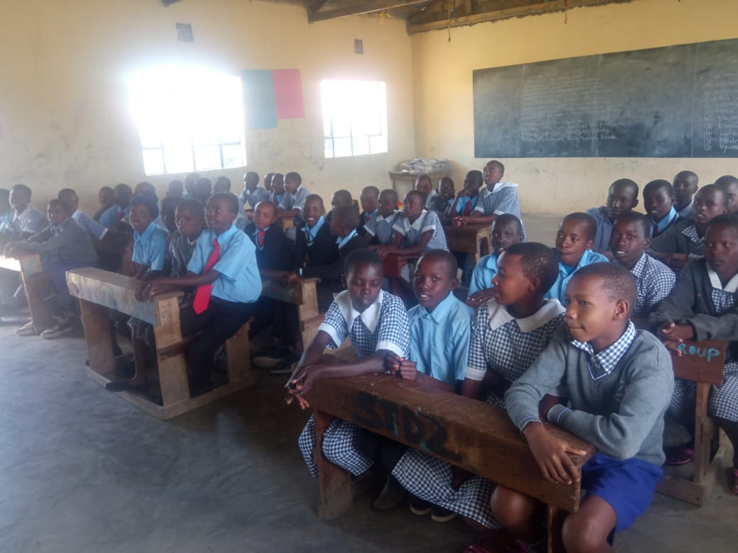A shortage of desks leads to students sitting three and four to desk designed for two.
