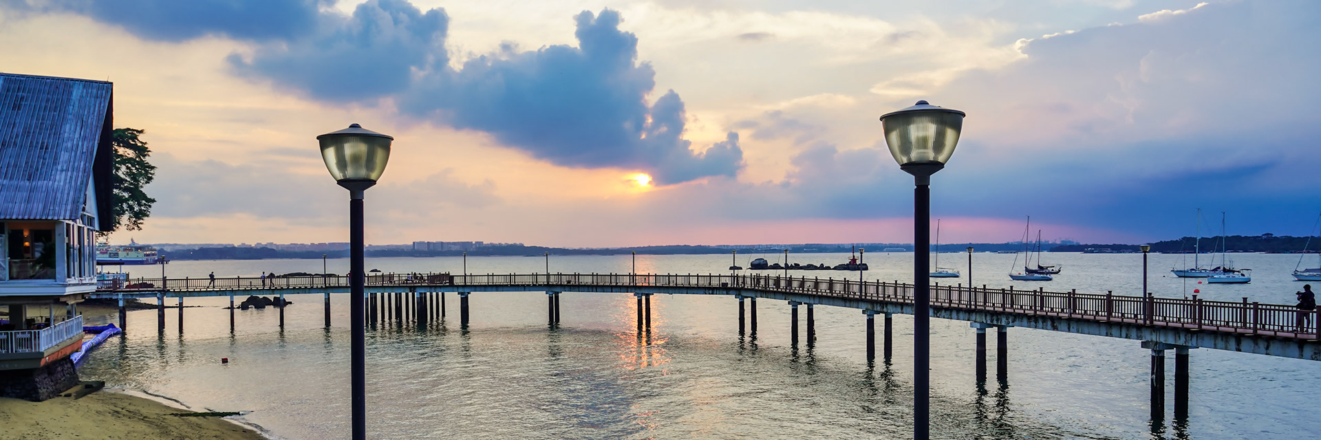 A wooden walkway takes you along the waterline at Changi Village to the sunset looking towards Singapore.