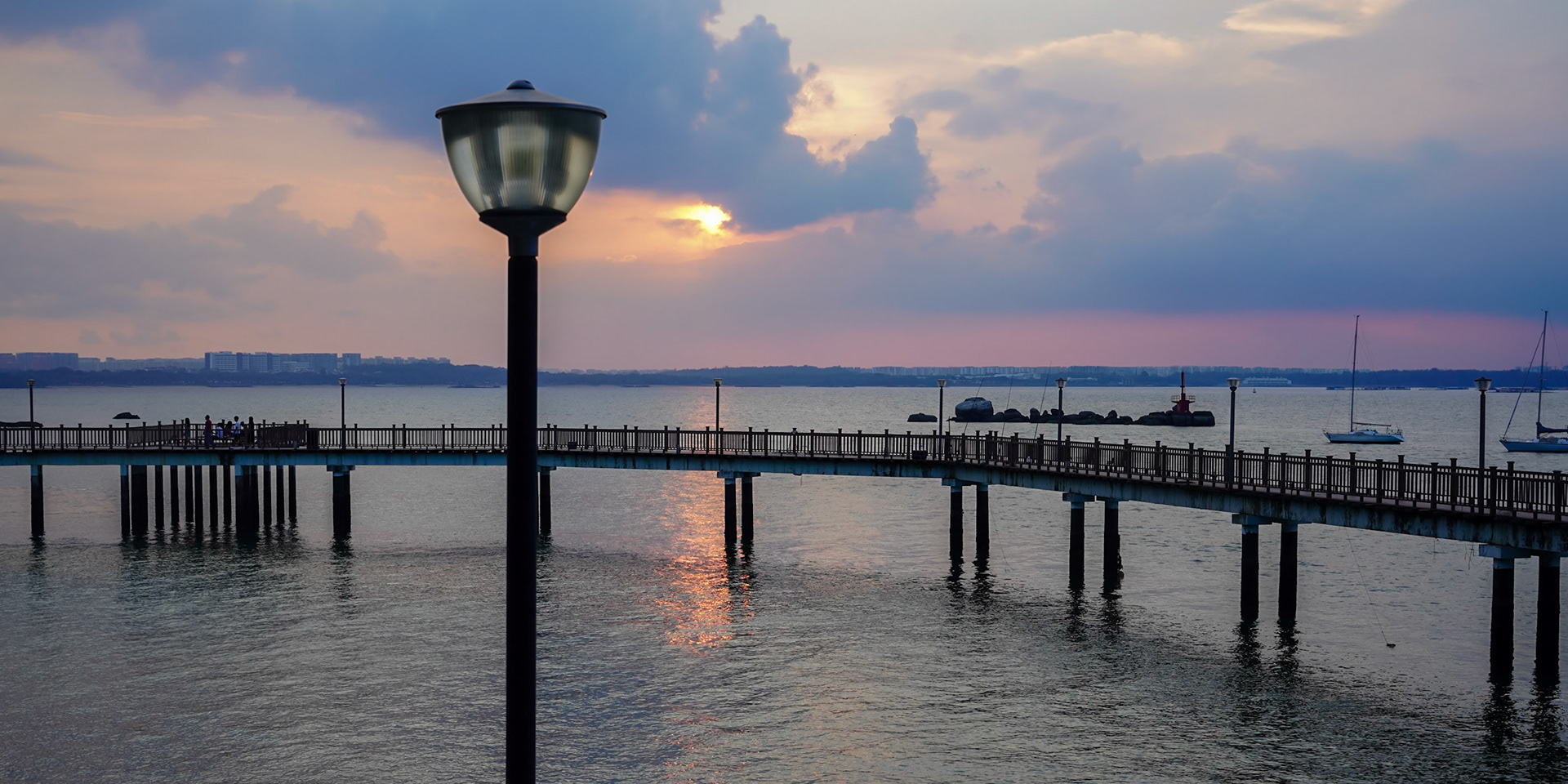 A wooden walkway takes you along the waterline at Changi Village to the sunset looking towards Singapore.