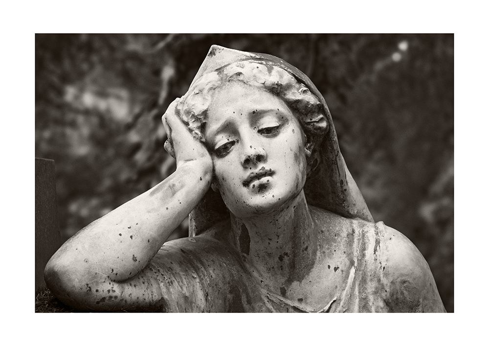 Bronze sculpture of a beautiful young woman with a sad, introspective gaze, her head supported by her right hand.