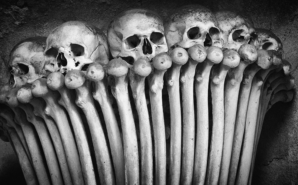 Six human skulls placed over various femurs form a decorative arch in an ossuary in the Czech Republic.