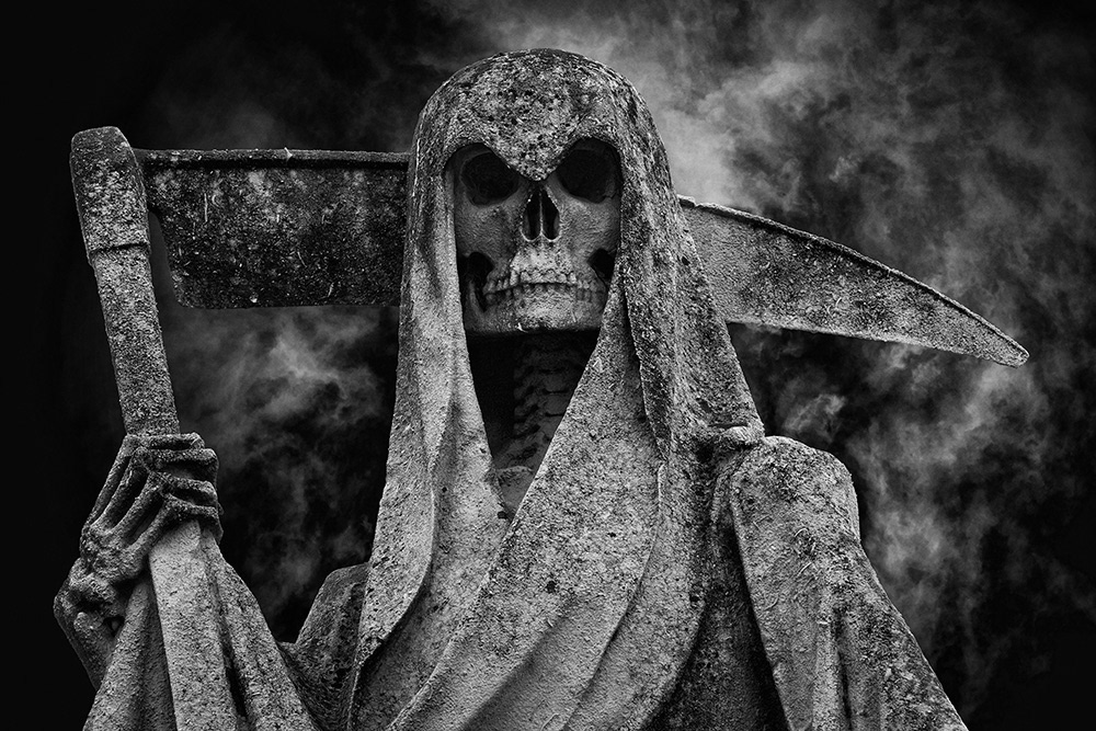 Sculpture of death, skull with sinister black eye sockets under hood, skeleton hand, gloomy night sky.