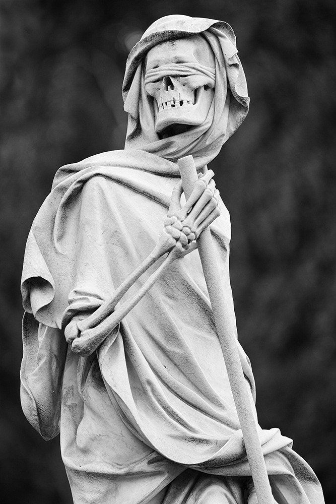 Death, as a merciless Grim Reaper, dressed in a robe and hood, his eyes blindfolded, indiscriminately seeks his victim.