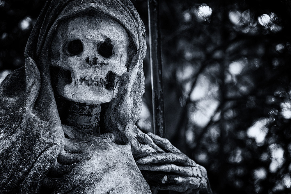 Death, dressed in a robe and hood, with a scythe in his bony hand, looks at us head-on with a heavily weathered face.
