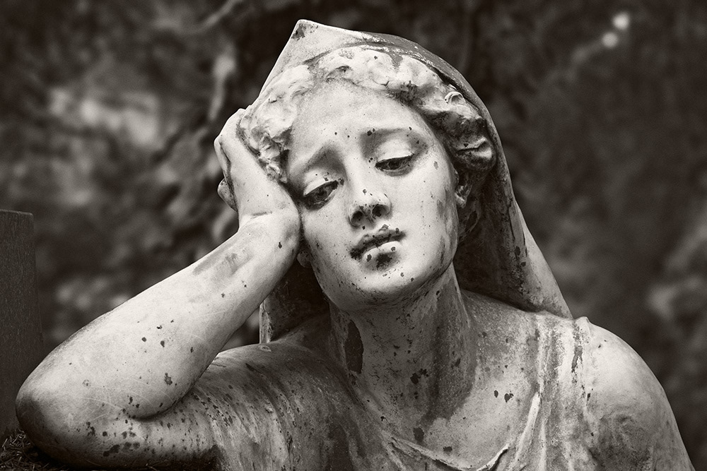 Bronze sculpture of a beautiful young woman with a sad, introspective gaze, her head supported by her right hand.