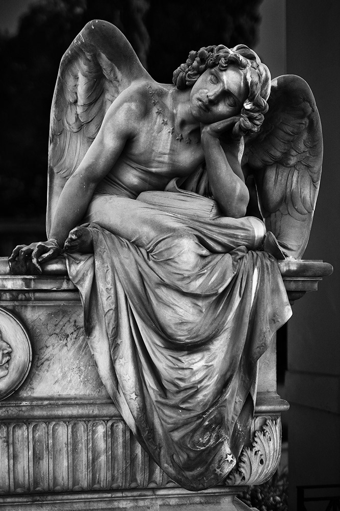 An androgynous angel, sitting on a sarcophagus, with a dreamy gaze, her head tilted to the side with curly hair.