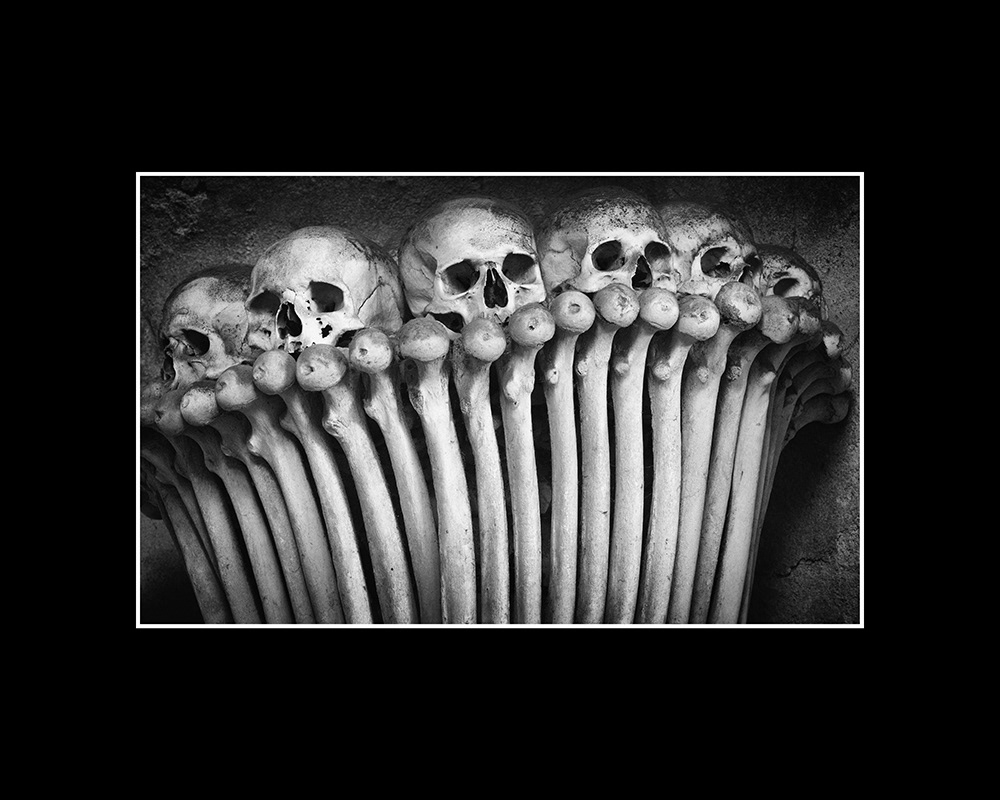 Six human skulls placed over various femurs form a decorative arch in an ossuary in the Czech Republic.