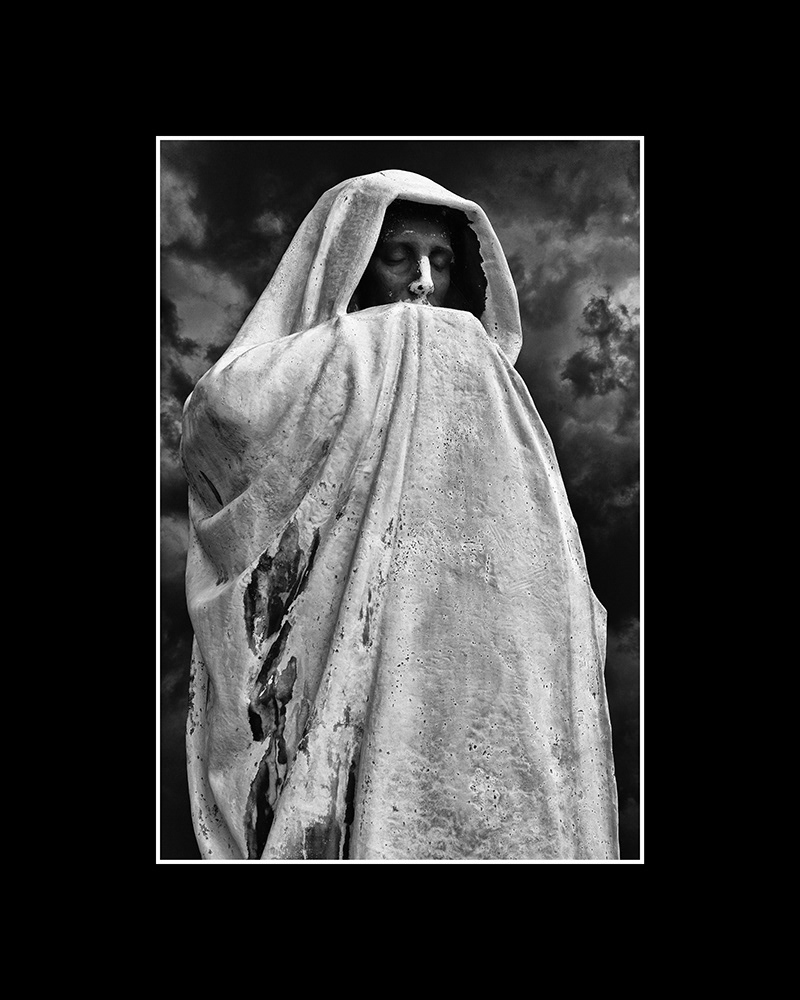 Death, draped in a long robe, stands silently with closed eyes in a Chicago cemetery, set against a dark, stormy sky.