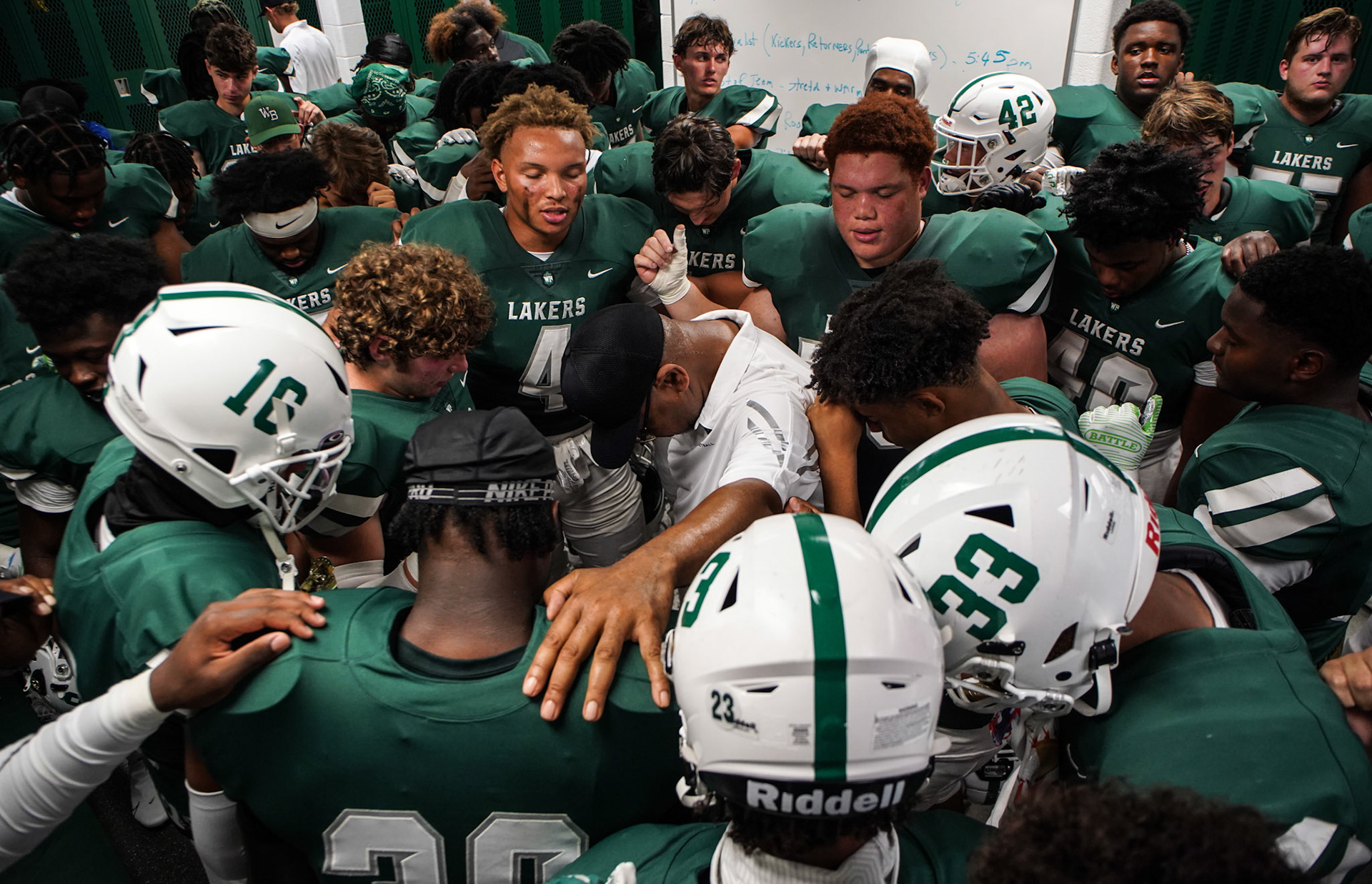 West Bloomfield coaches and players recite the team poem in the locker room before heading to the field for the season opener between the West Bloomfield Lakers and the Rochester Adams Highlanders in West Bloomfield on Friday, Aug. 27, 2021.