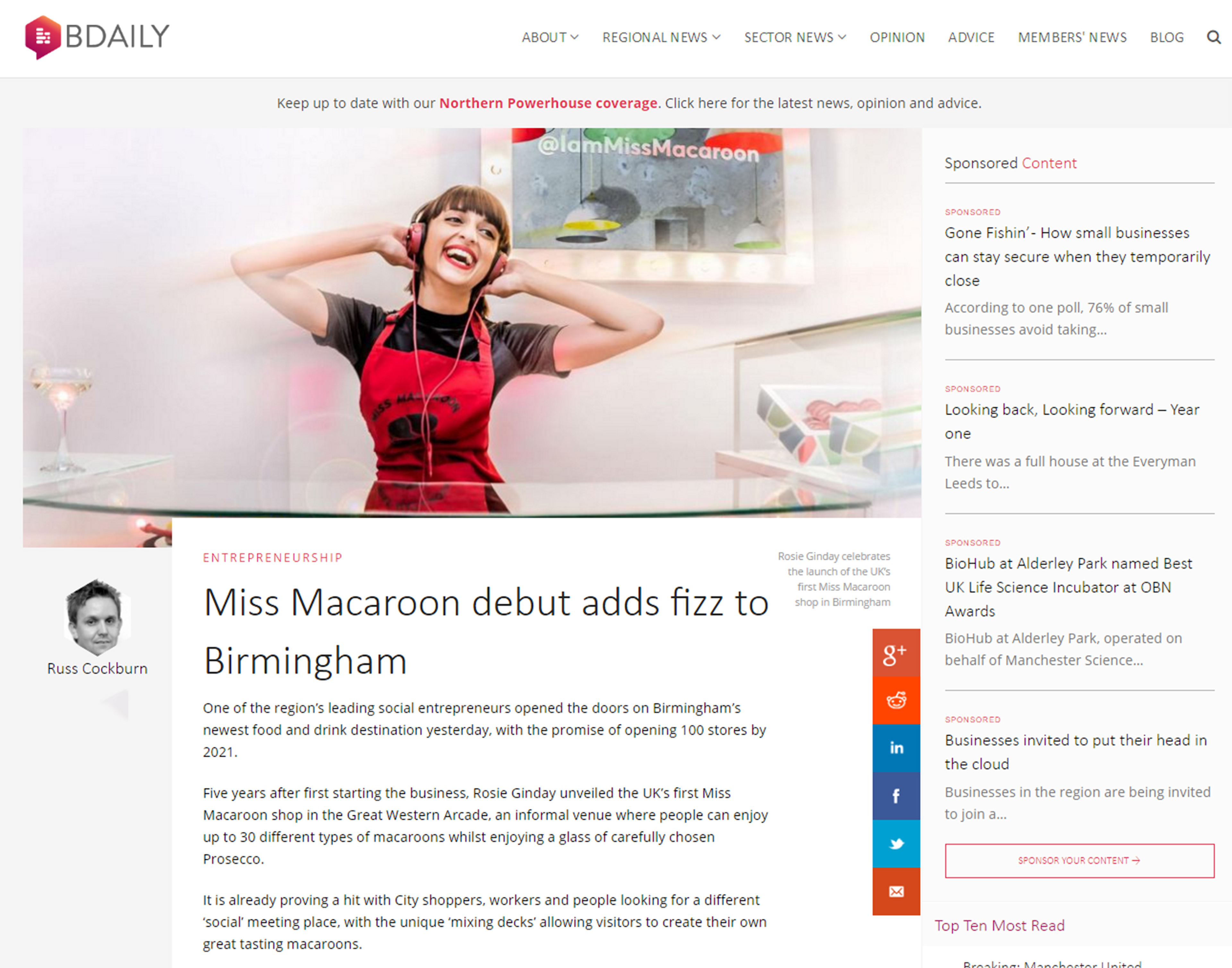 Rosie Ginday in a red apron and headphones smiles joyfully behind a counter with a glass of Prosecco. The headline reads, "Miss Macaroon debut adds fizz to Birmingham."