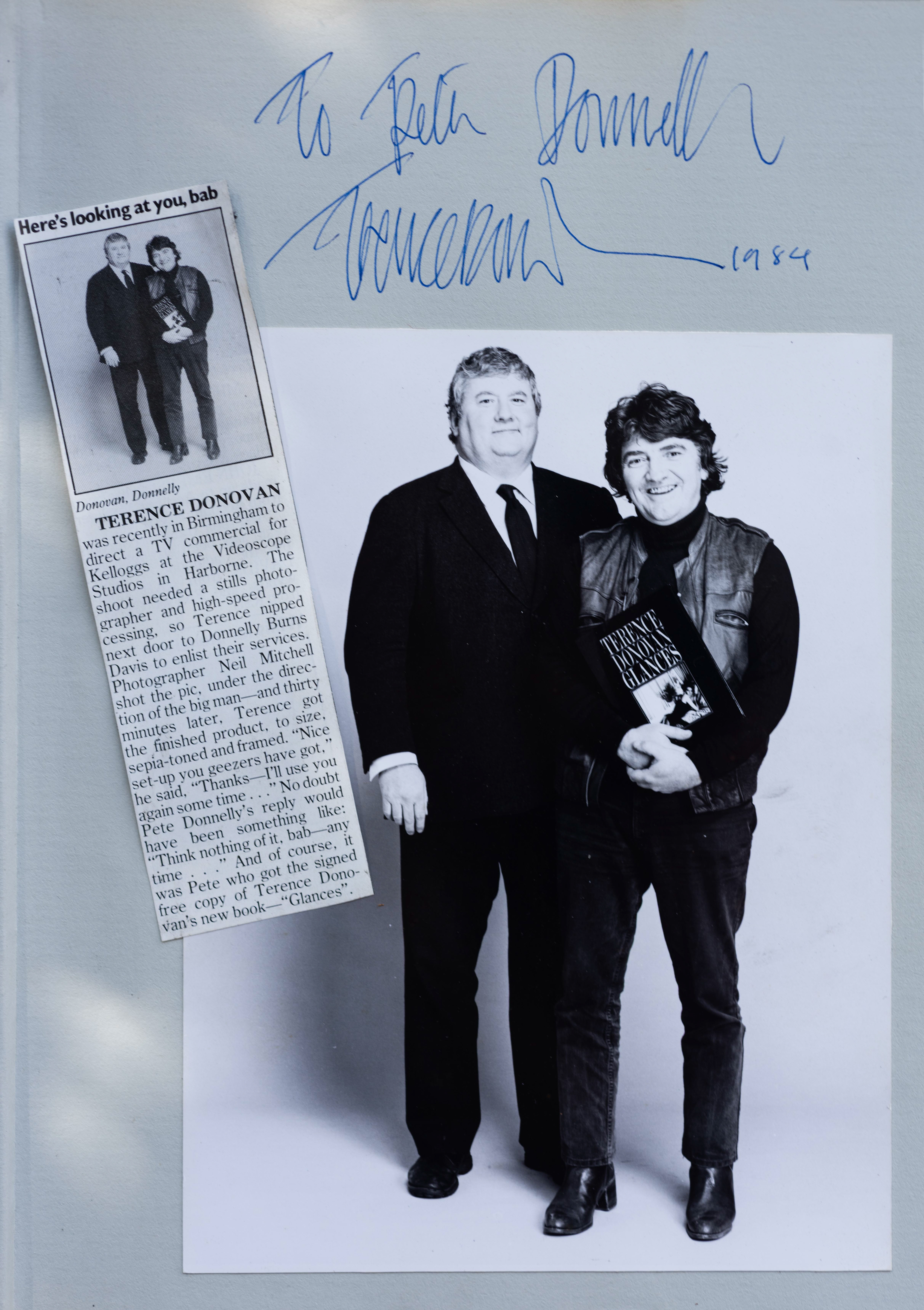 Black and white photo of two men; one holds a book, “Terence Donovan Glances.” Above is a blue autograph, beside a newspaper clipping. Terence Daniel Donovan FRPS & peter joseph donnelly @ park hill studios Harborne Birmingham