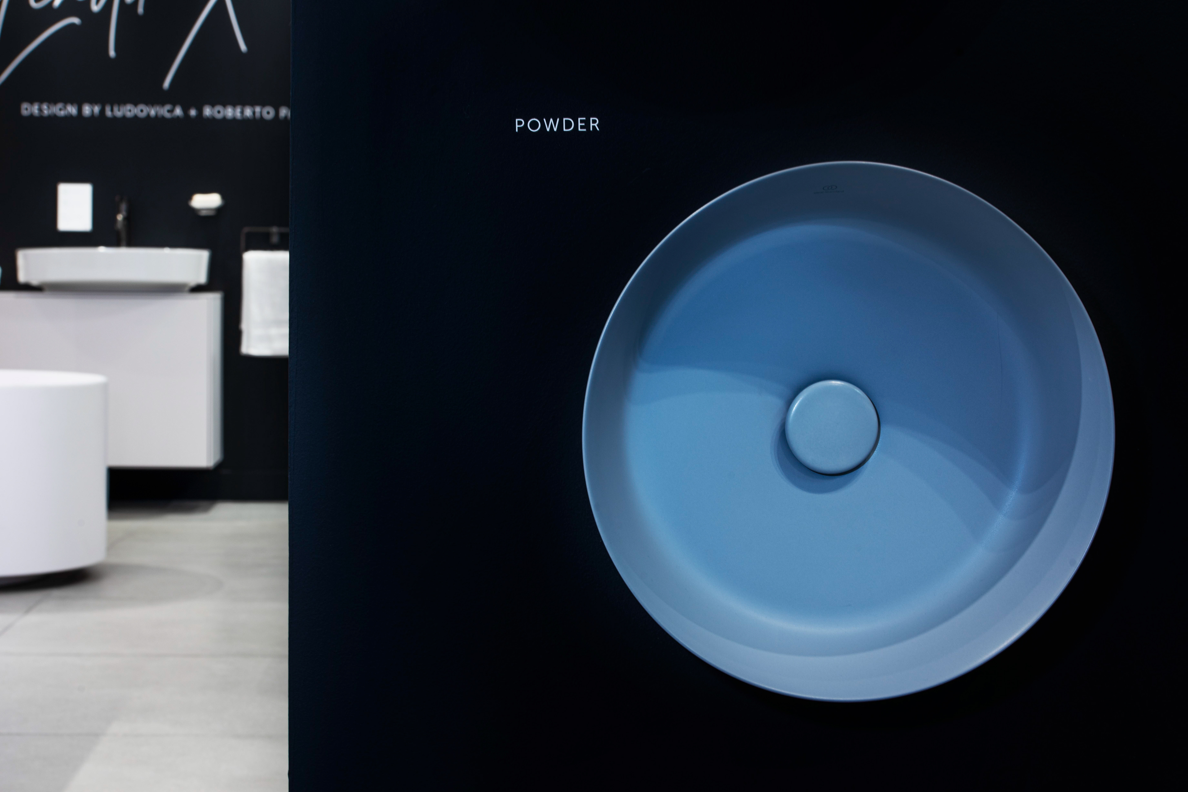 Modern sink in Oxford showroom interior Powder Blue. A modern bathroom showroom with a close-up of a sleek, round, blue basin on a dark background. Minimalist aesthetic.