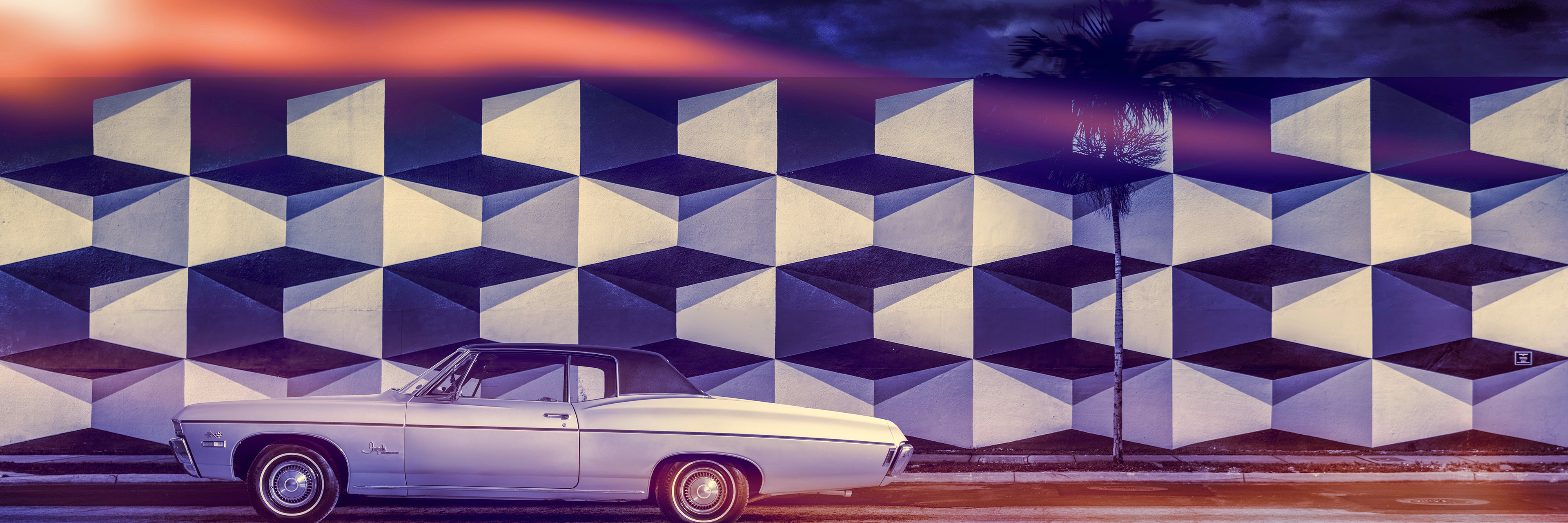 Classic white convertible car parked in front of a geometric mural with black and white 3D cubes. Palm tree silhouette under vibrant sunrise sky.