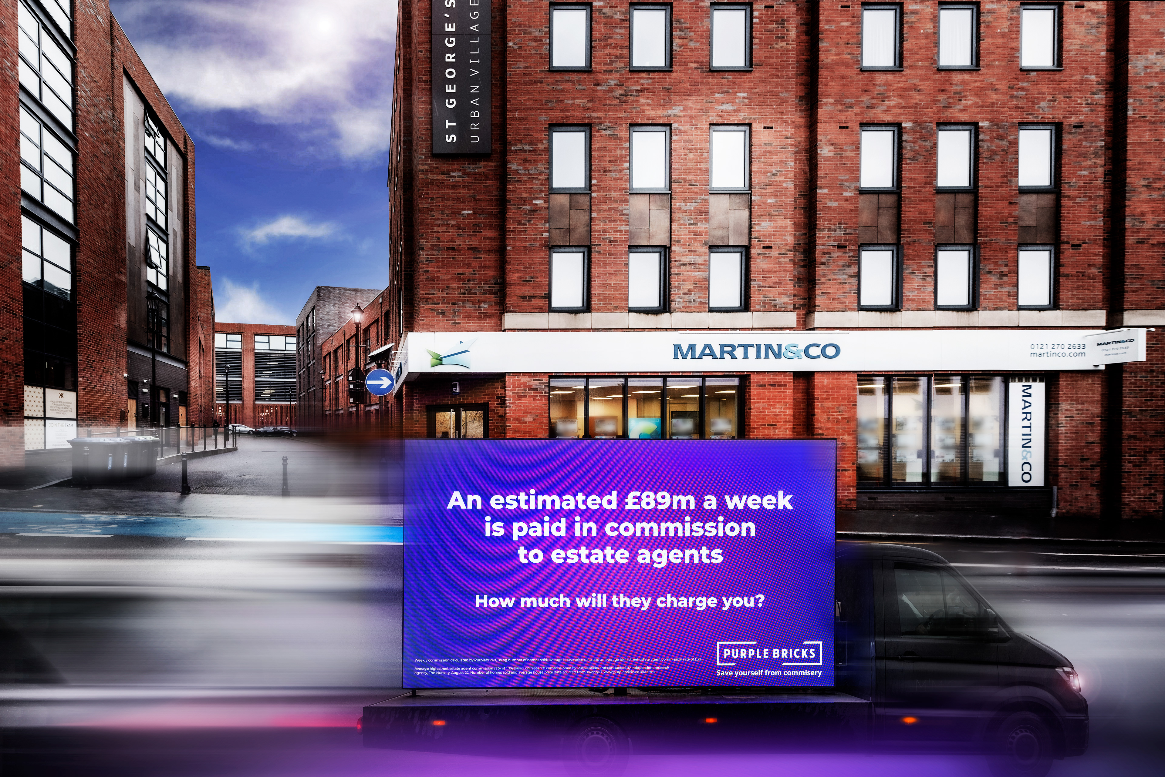 A digital billboard truck with a vibrant purple sign reads, "An estimated £89m a week is paid in commission to estate agents," parked outside a red brick building. Photographer Hockley Birmingham