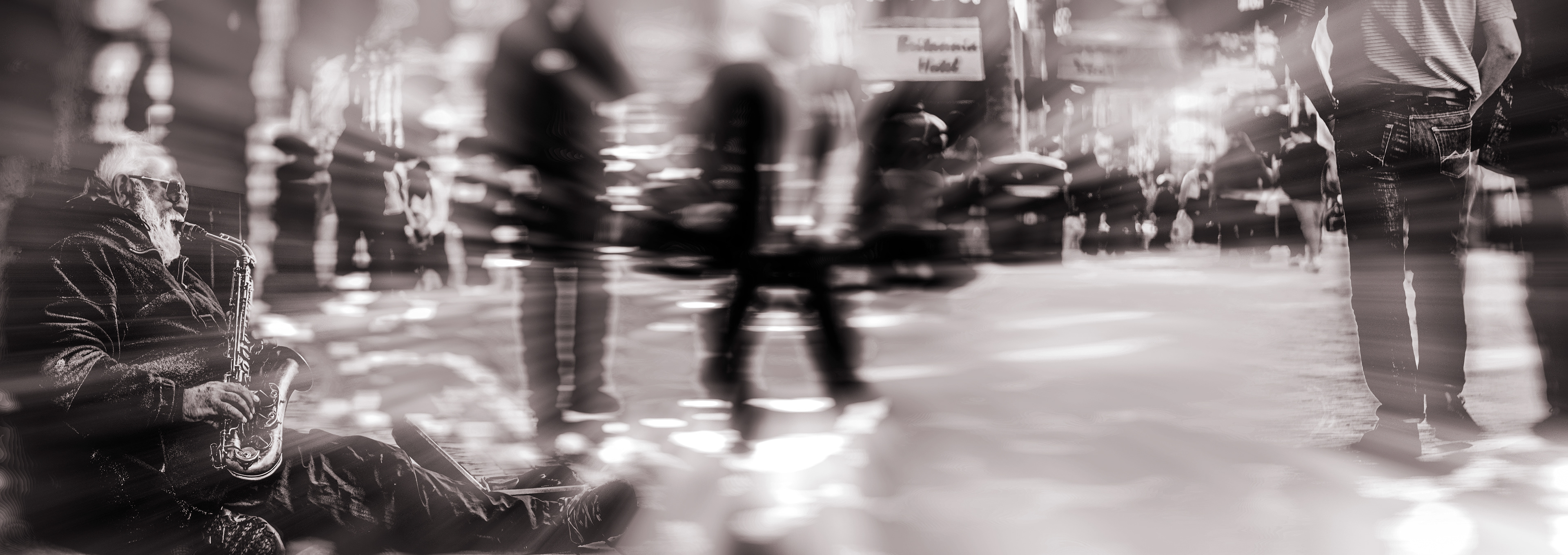 Elderly man plays saxophone on busy street in sepia tone, creating a lively yet nostalgic atmosphere. Blurred pedestrians add a sense of motion.