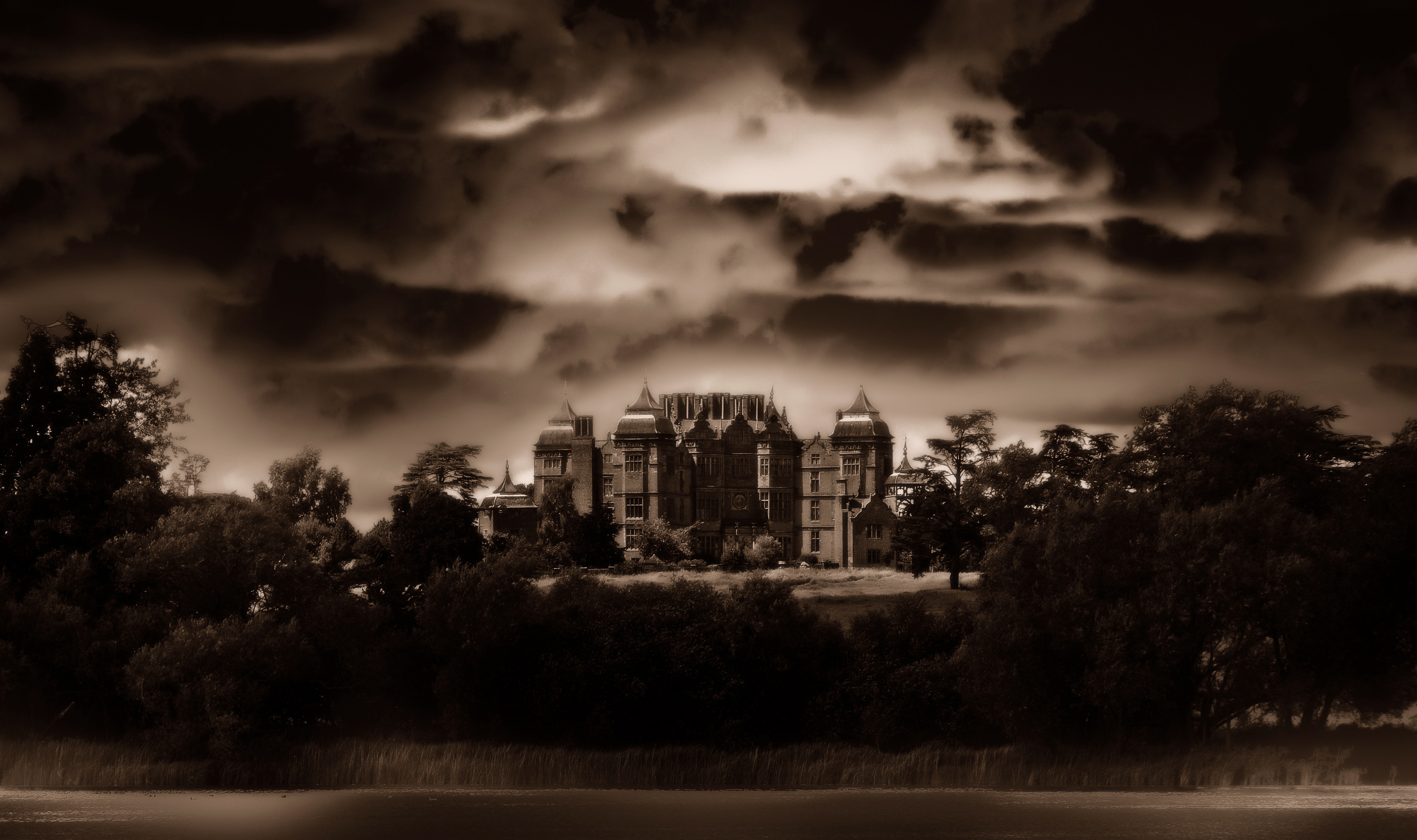 Sepia-toned image of a grand, eerie mansion with towers, surrounded by trees under a dramatic, cloudy sky. Gothic atmosphere conveyed.. westwood house worcestershire