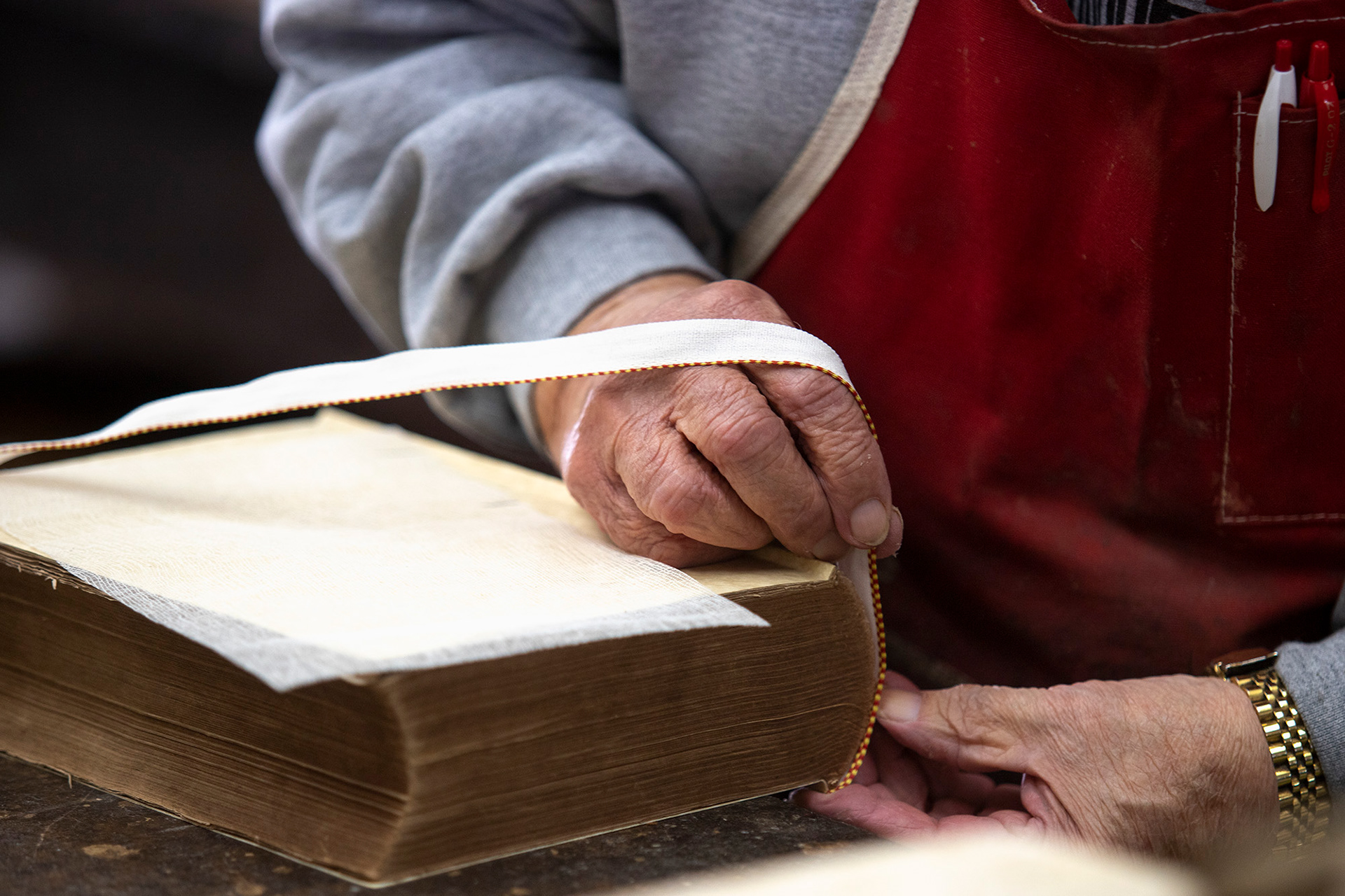 Ron Bowman puts a new decorative edge on an old book before the cover is glued on. Although it is often seen on books and many assume it is from the sewing of the pages, this edging has no purpose other than the aesthetic it provides.