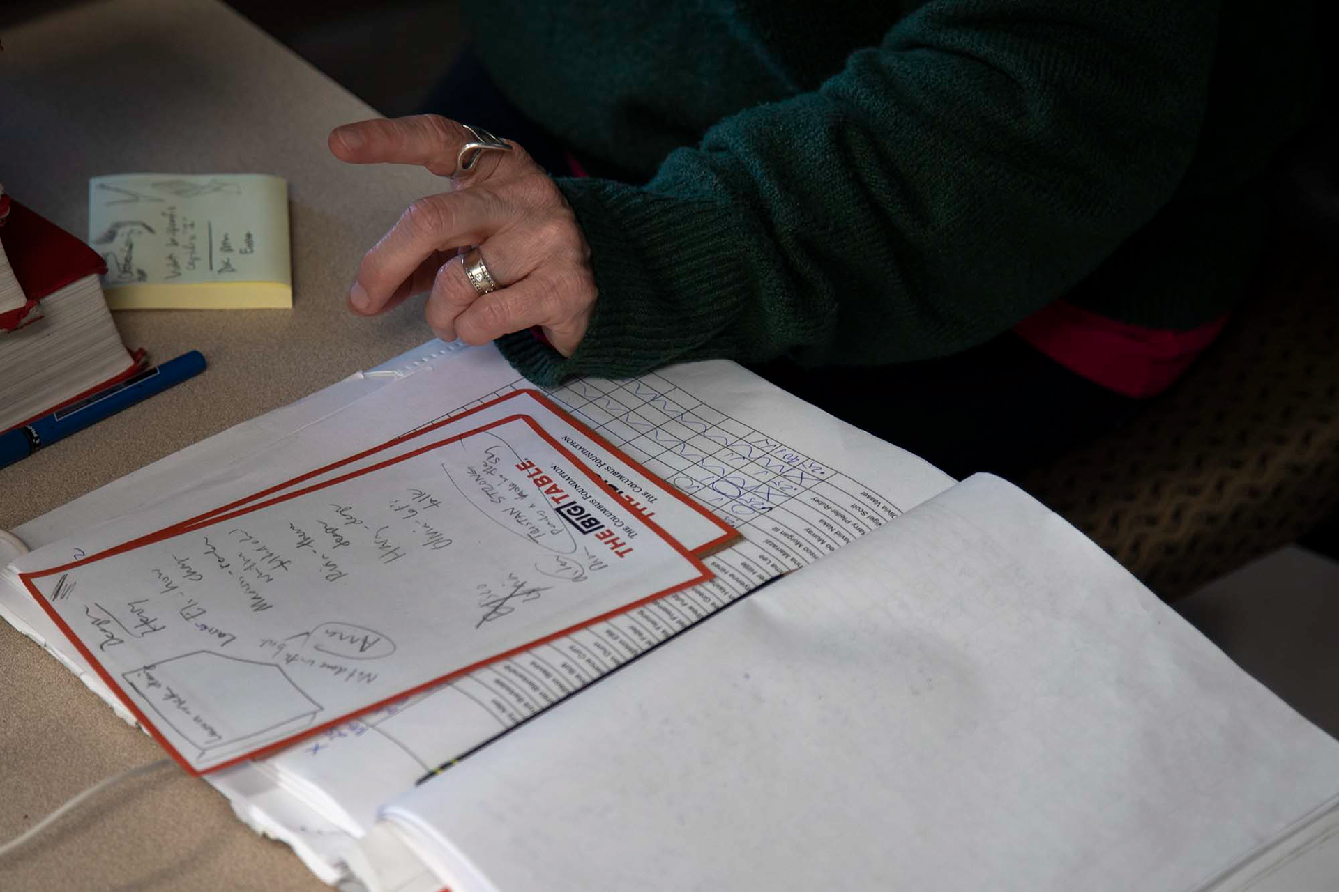 Trina Marschall marks down students' grades in her grade book and makes notes on what needs to be changed as she looks through their individual slides that come together to create a thank you slideshow for a past class presenter.