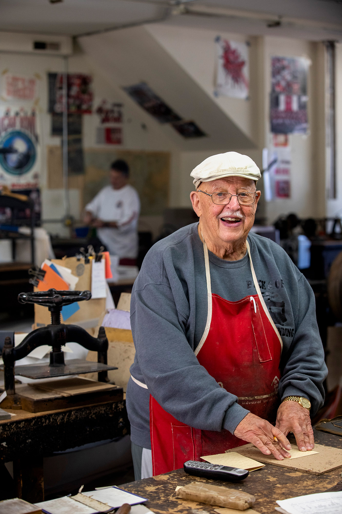 Ron Bowman looks up from his work of making inlet pages for an old book he is refurbishing. Ron loves his work and often whistles along with the radio as he restores antique books and their covers.