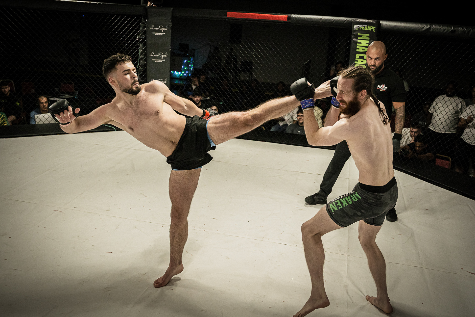 2 MMA Fighters fighting in a ring shot by a photographer. High kick to the head.