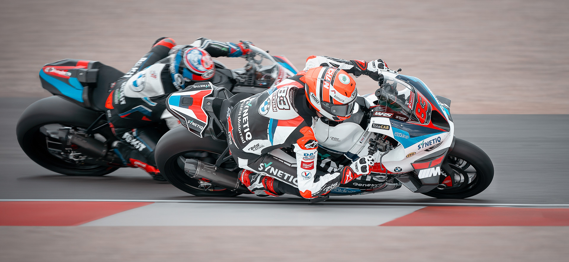 Two motorcycle racers in full gear, with bike numbers 83 and 88, competing closely on a race track shot by a professional motorsport photographer.