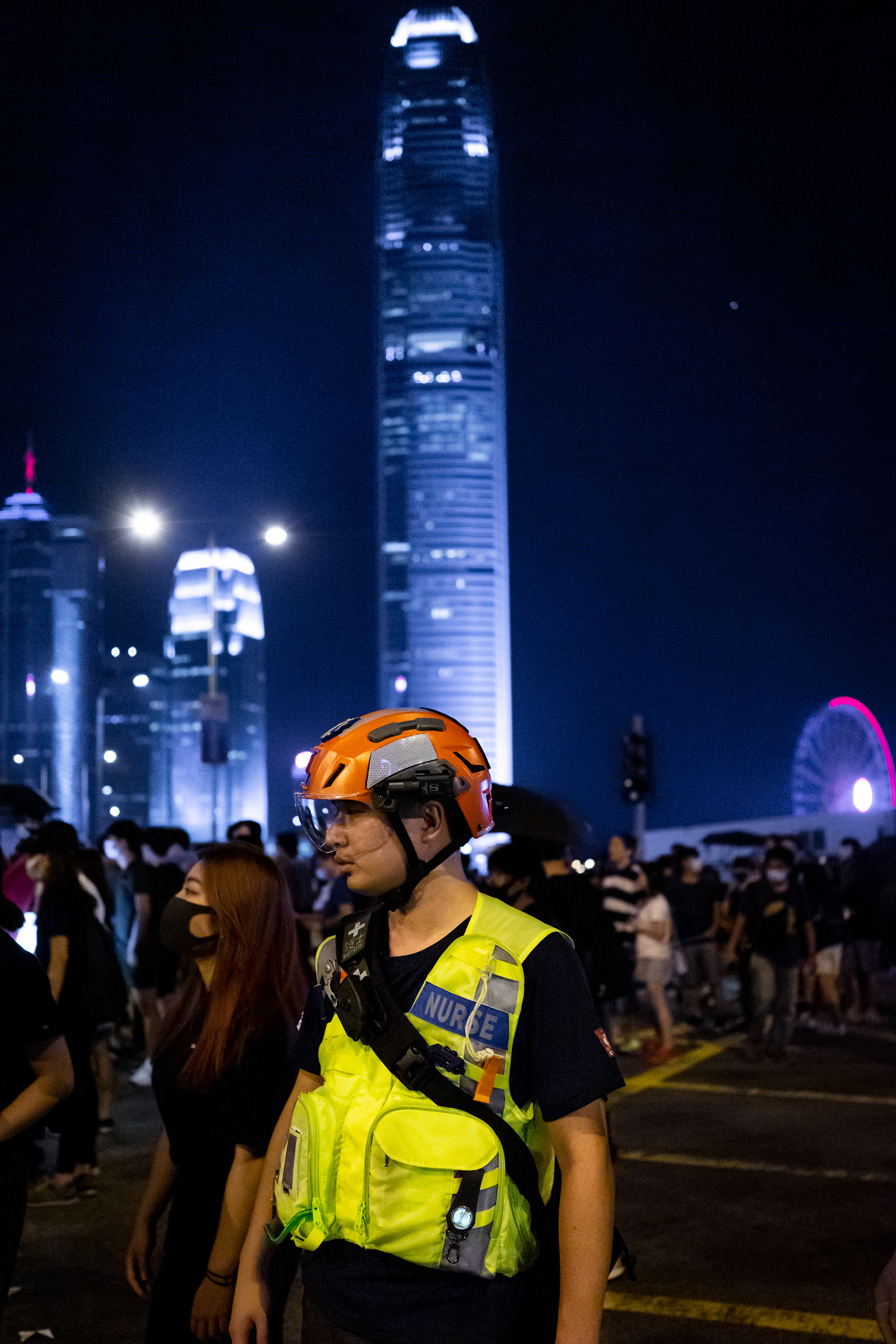 Nok: Admiralty, Hong Kong: Nok, the leader of a volunteer EMS team observes the action and scans the crowd for potential injuries. Citizens gathered at Tamar Park to commemorate the fifth anniversary of the Umbrella Movement protests. September 28, 2019-Hong Kong