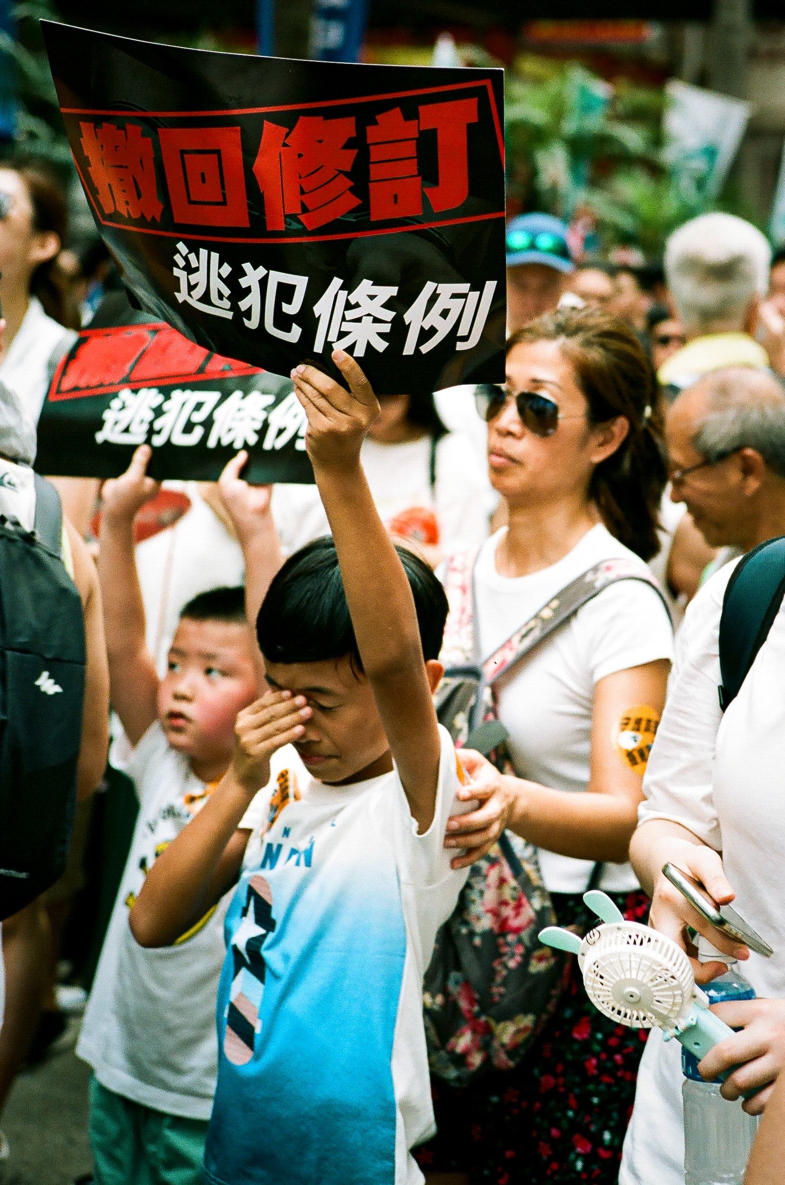 Admiralty, Hong Kong: A young Hong Konger endures the heat while marching with his parents and brother. Hong Kongers march through the Admiralty in a massive public display against a proposed law that would allow for Hong Kong citizens to be extradited to China upon arrest. Hong Kong, 35mm
