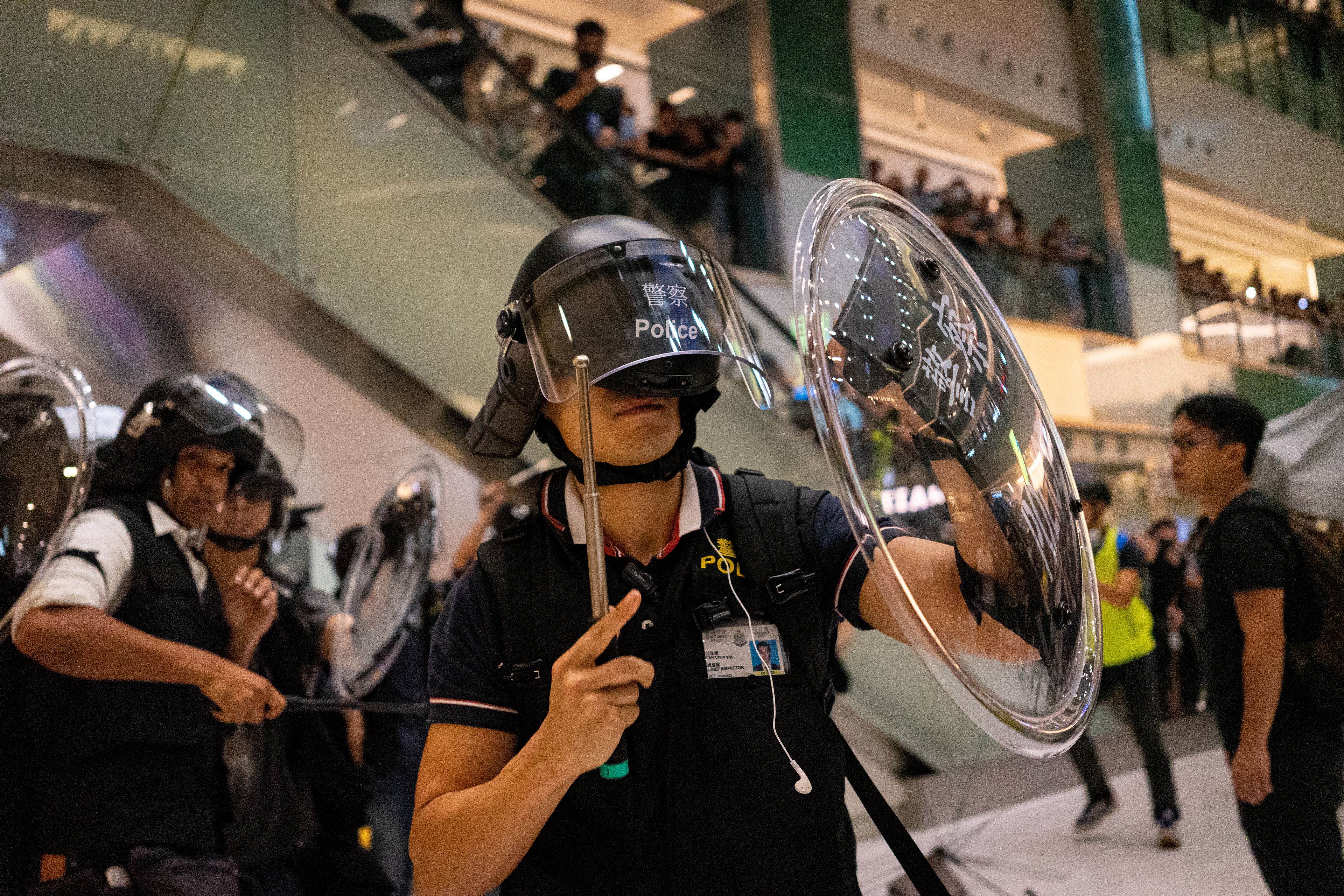 An officer has his helmet knocked askew by flying objects. A protest in the Sha Tin suburb of Hong Kong was largely peaceful, until police pursued protestors into the New Park Mall. July 14, 2019-Hong Kong