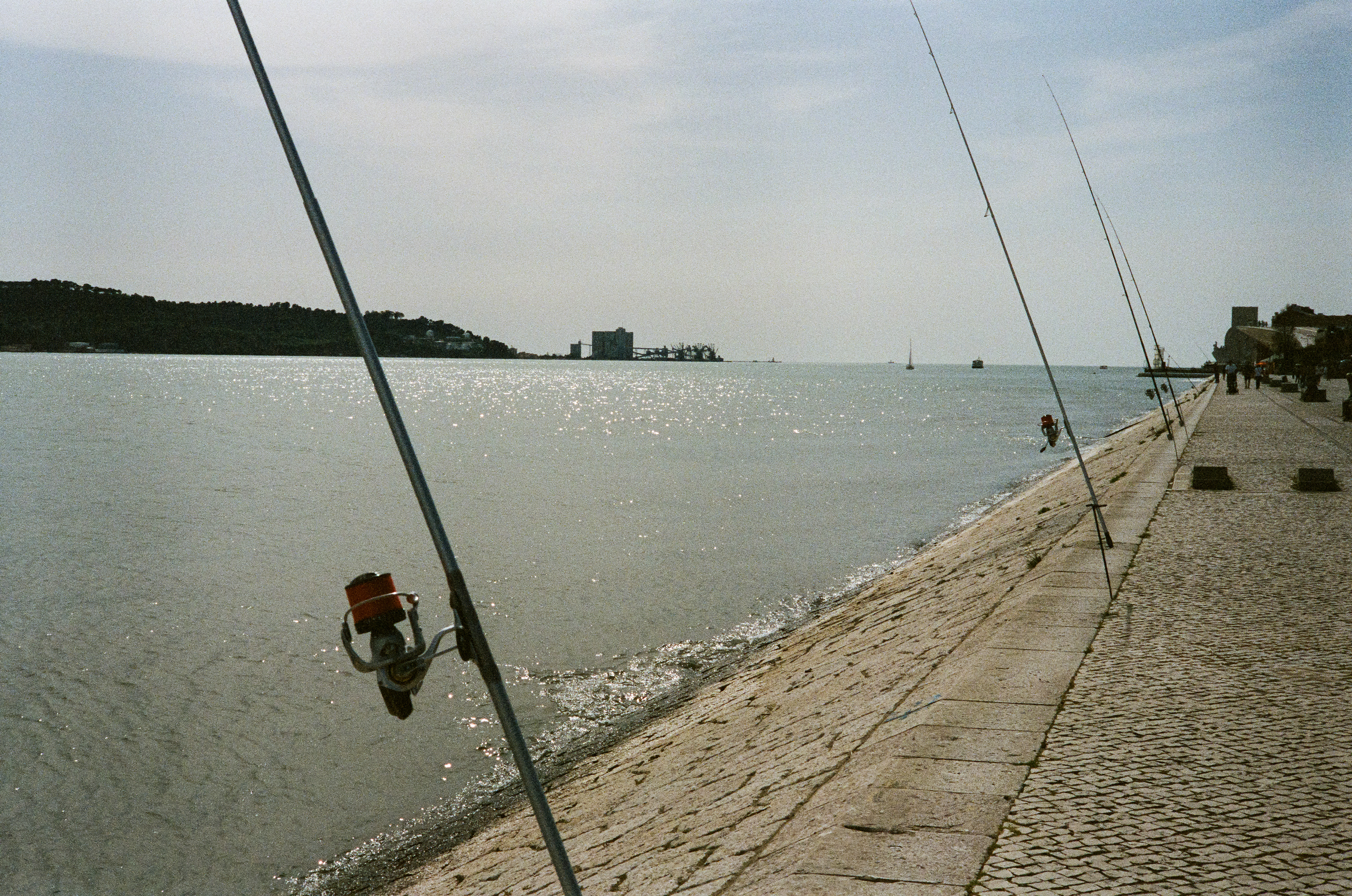 Fishing: Along the banks of the Tagus, solo fishermen tend to multiple poles. Portra 400. April 3, 2023-Lisbon, Portugal-Photo by Aaron Guy Leroux