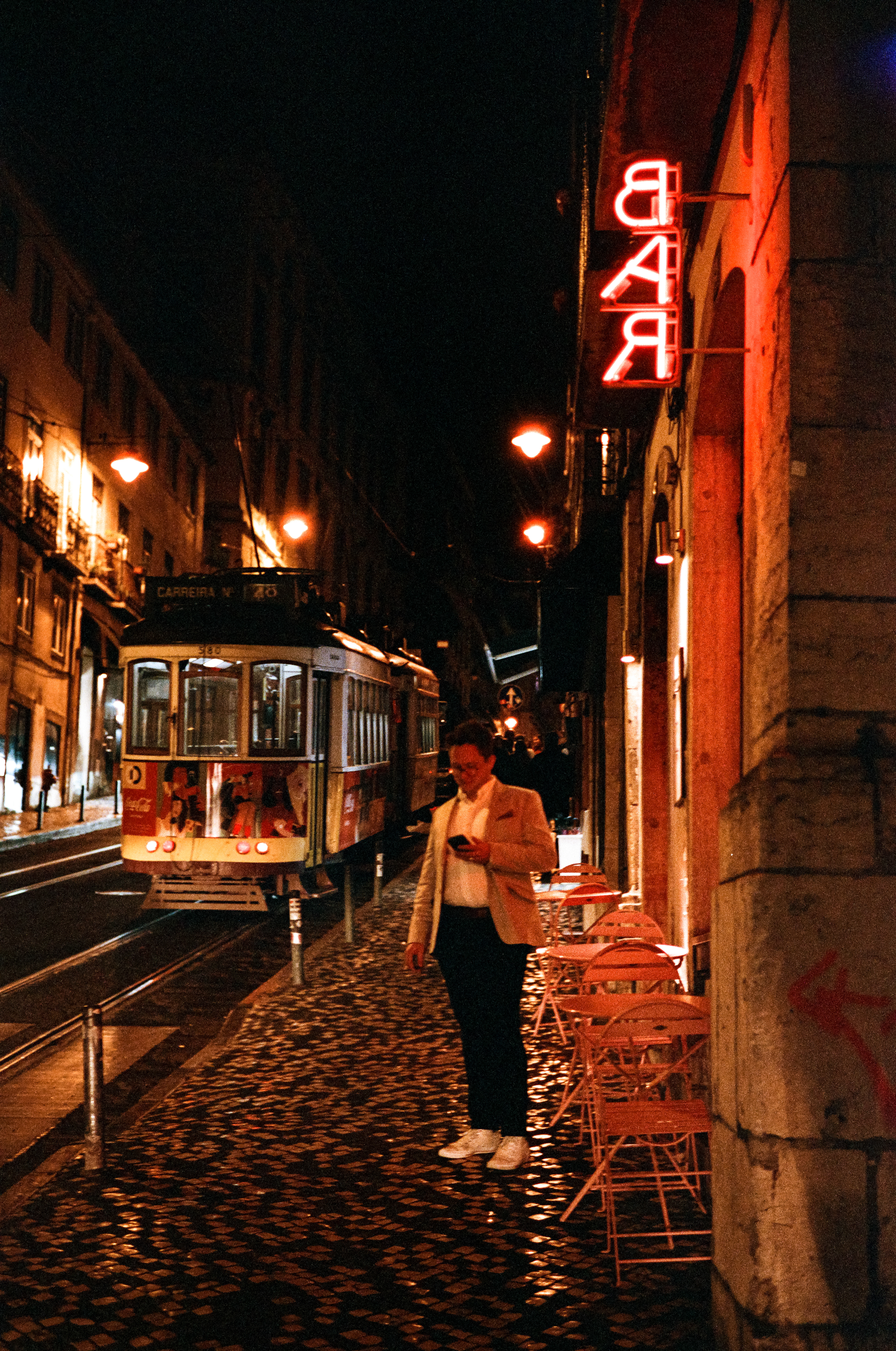 Dinner Plans: Night has fallen, cocktails consumed, people are looking for dinner all over Lisbon. A family enjoys dinner on a quiet street in Lisbon. Portra pushed to 800.April 1, 2023-Lisbon, Portugal-Photo by Aaron Guy Leroux