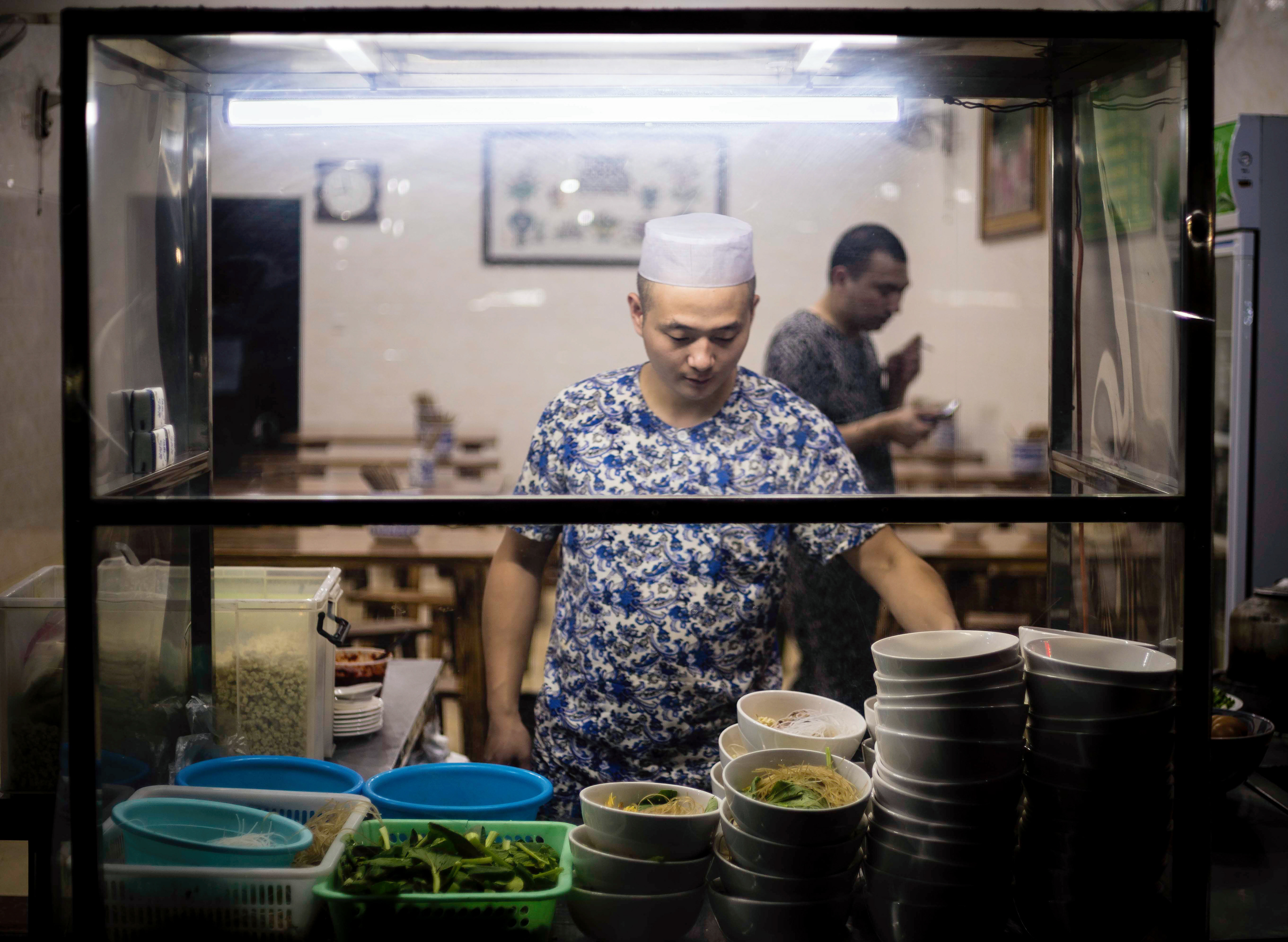 A Muslim man prepares his noodles for the evening rush in the Muslim Quarter. Xi'an, China.